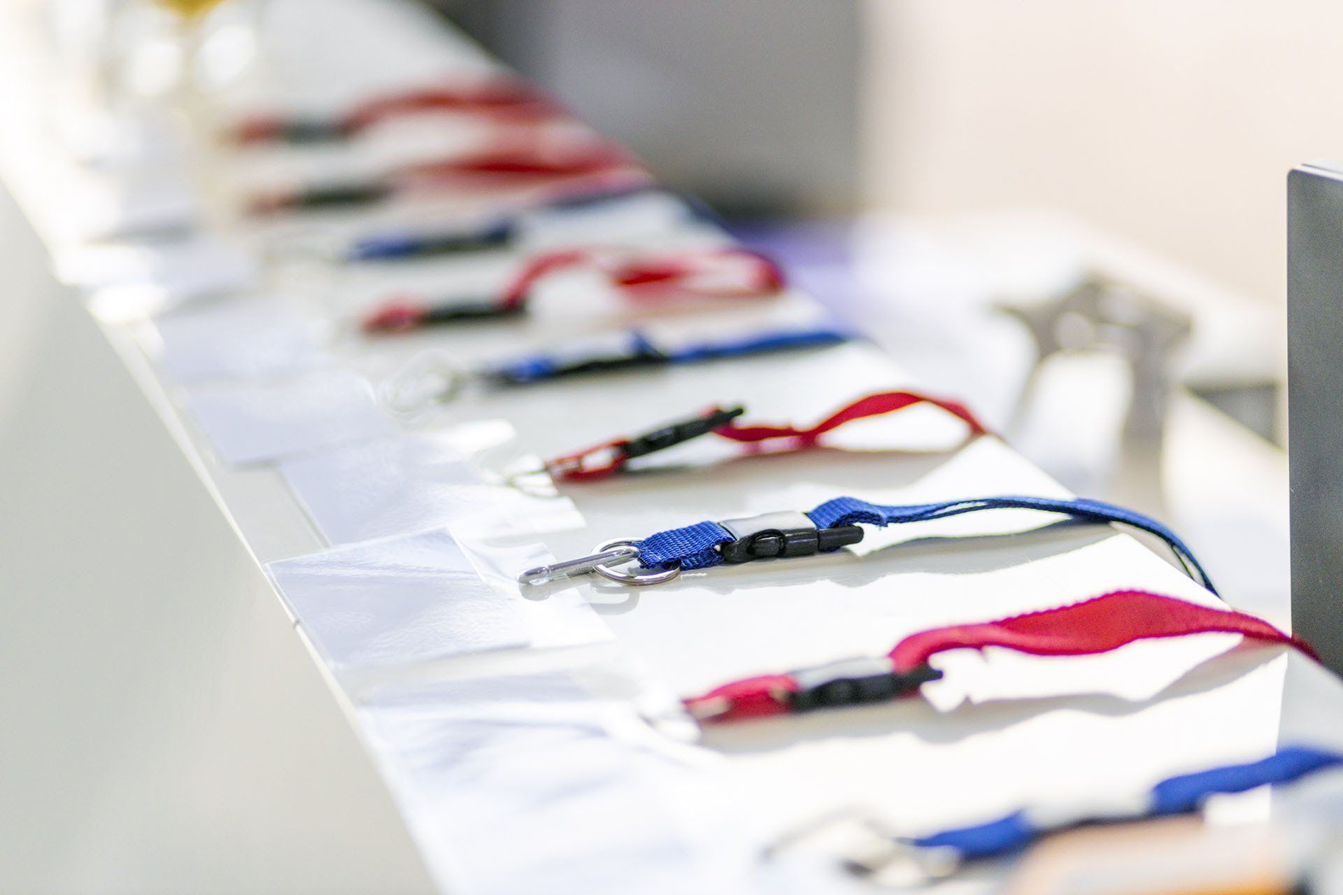 A row of lanyards are lined up on a table.