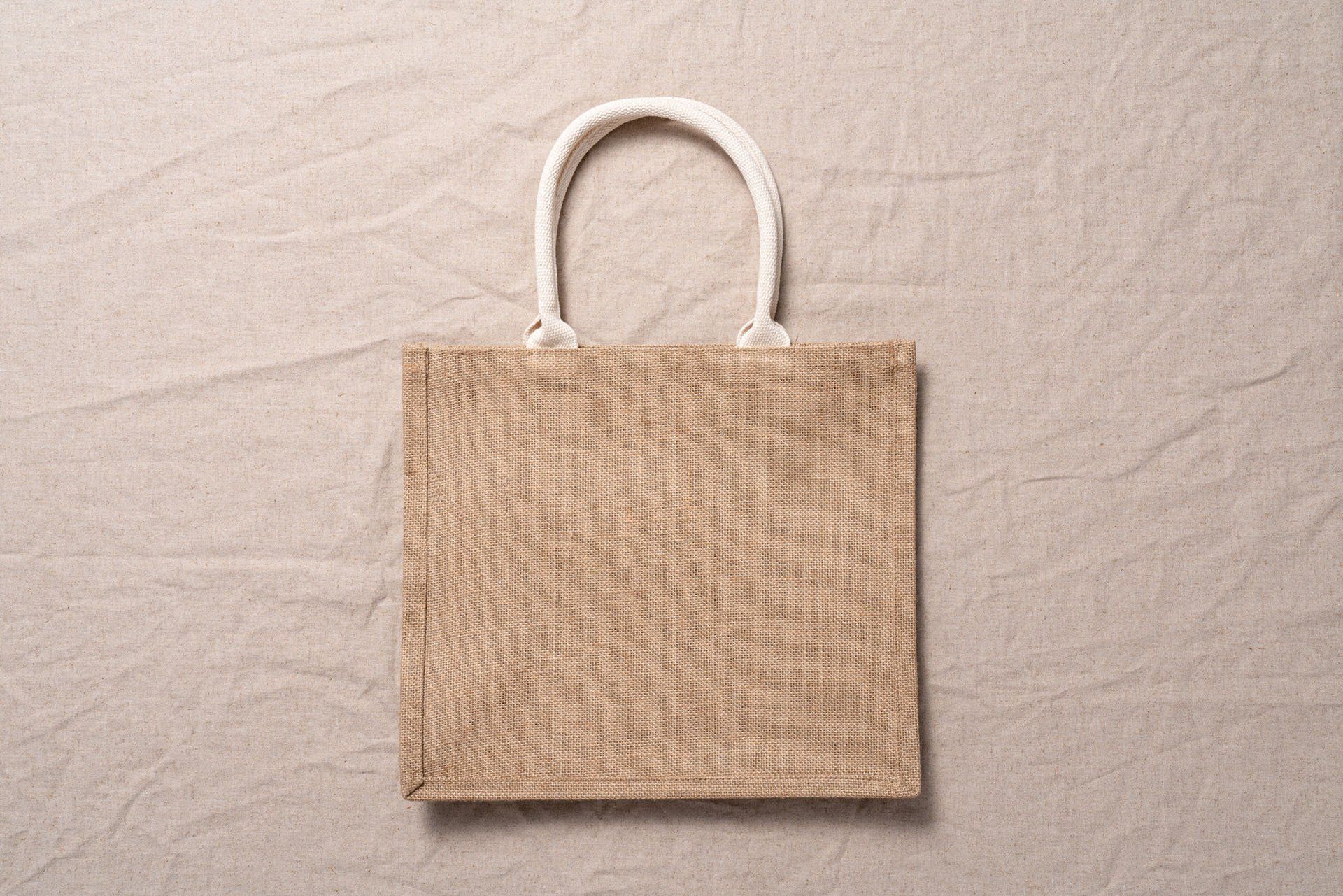 A small jute bag with a white handle is sitting on a table.