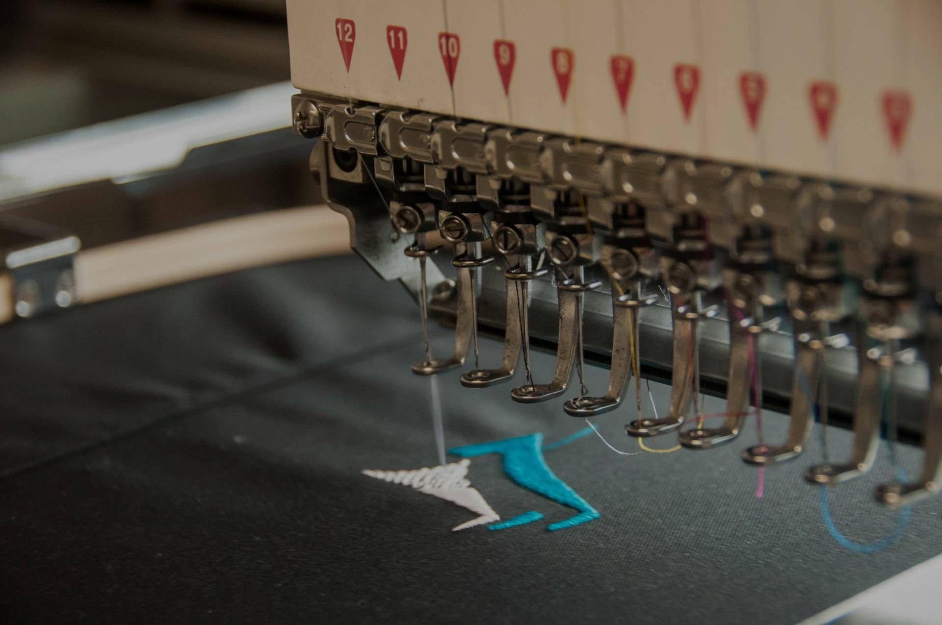 A close up of a sewing machine embroidery a logo on a piece of fabric.