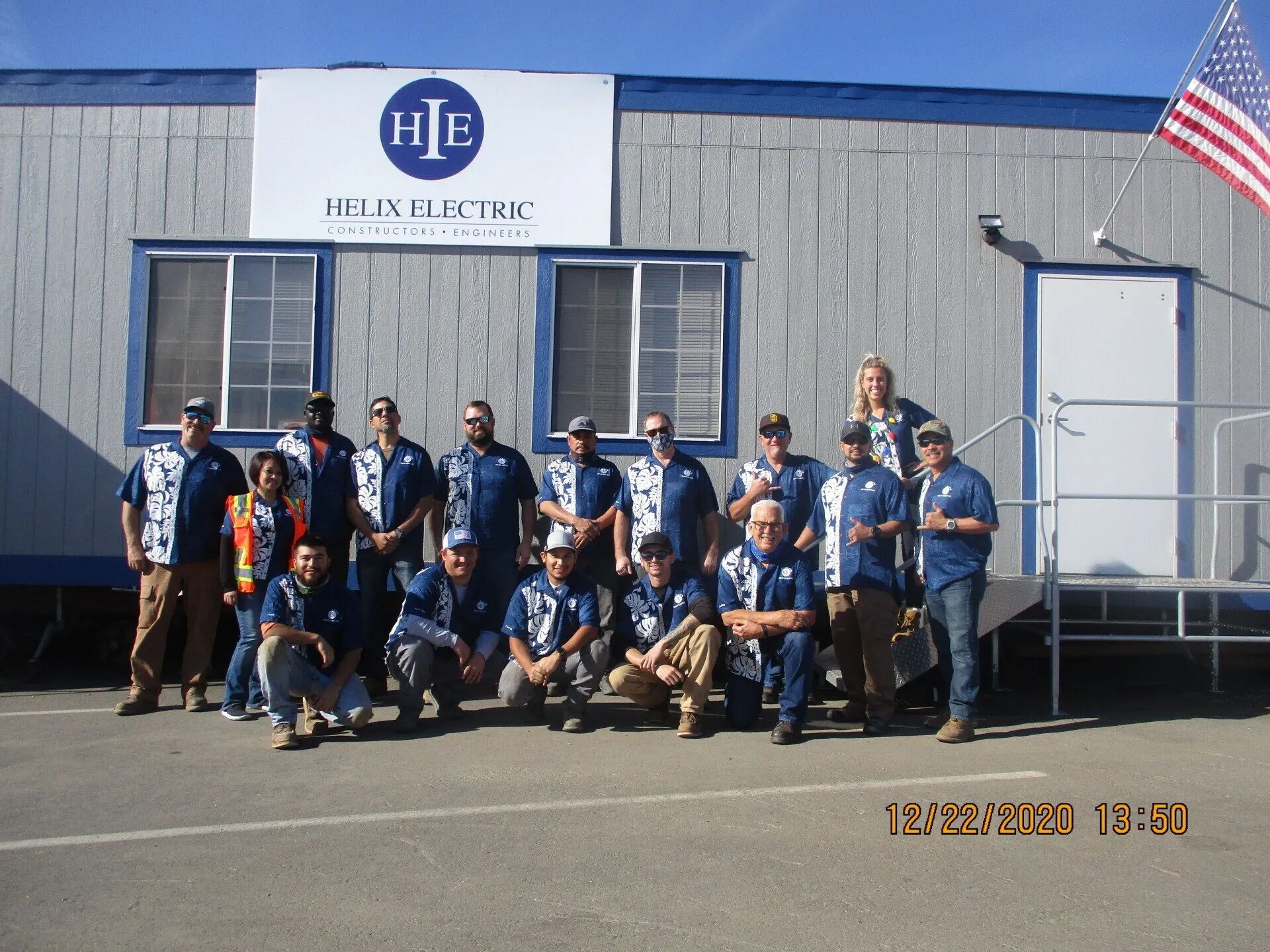 A group of people posing in front of a helix electric building