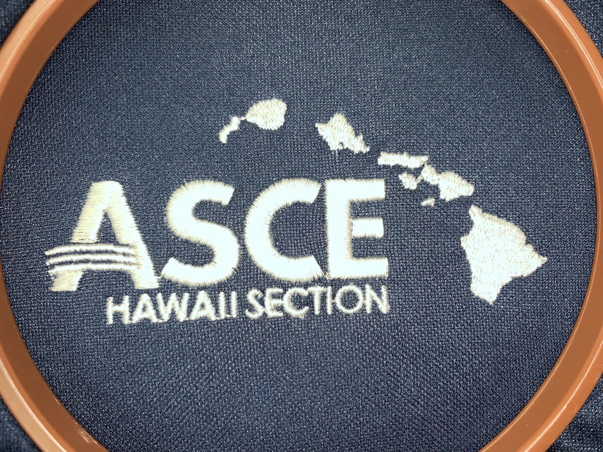 A hawaii section logo is embroidered on a blue shirt