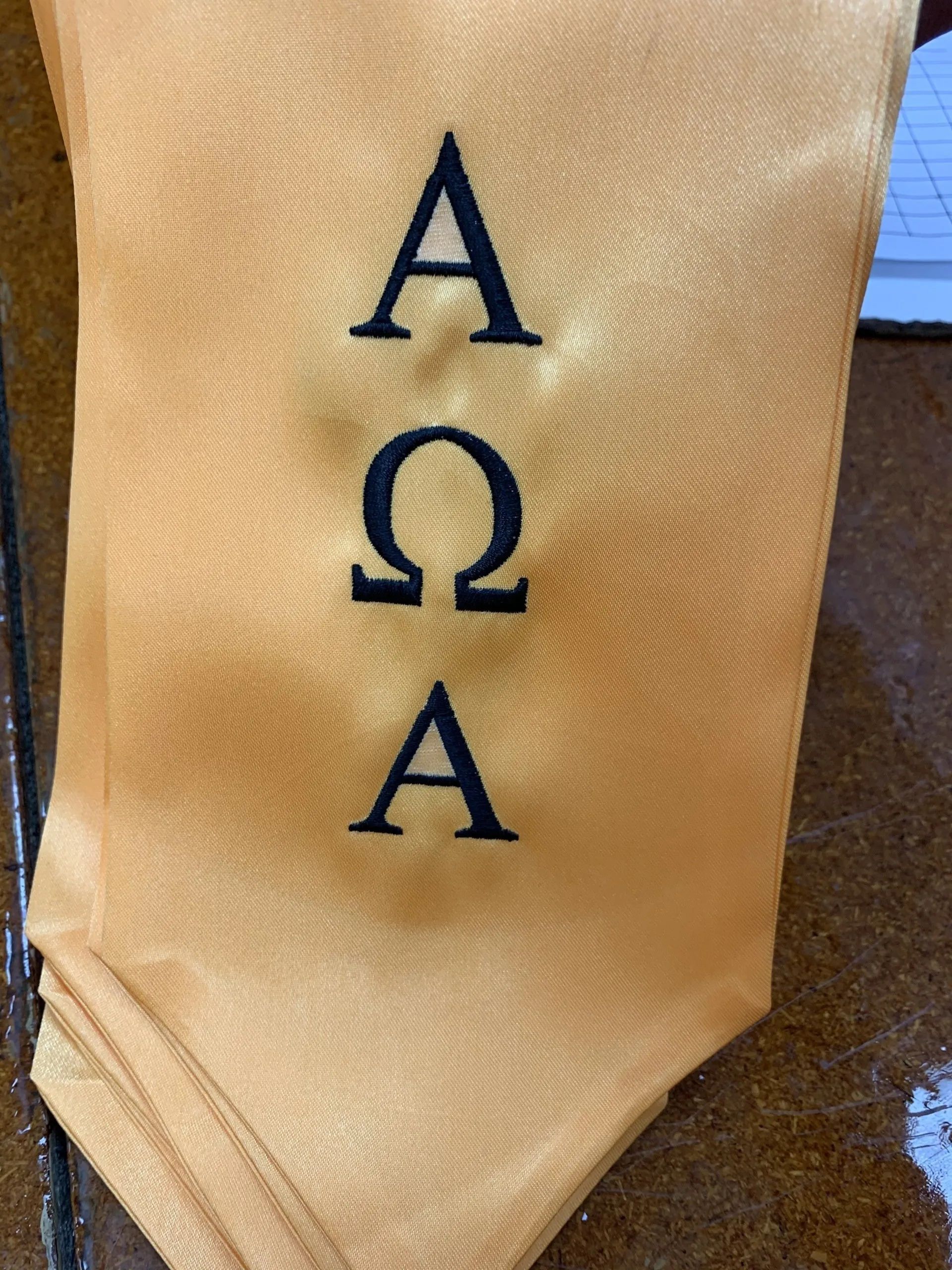 A yellow scarf with the letters a o and a embroidered on it