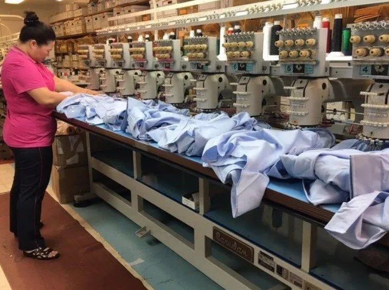 A woman in a pink shirt is working in a factory