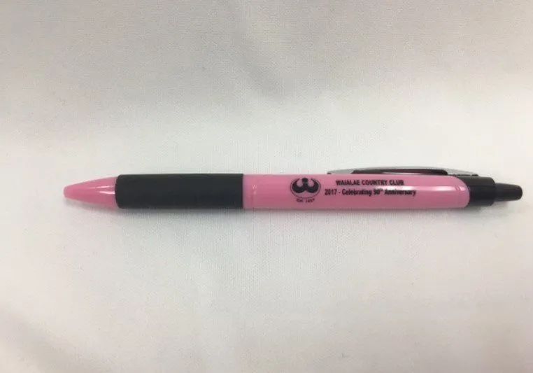A pink pen with a black grip is sitting on a white surface.