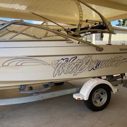 A white boat is parked on a trailer under a canopy — Cairns Custom T-Shirts In Cairns City, QLD