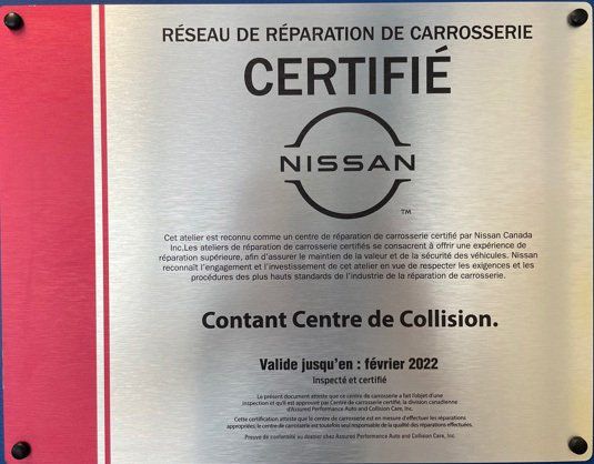 Panneau du réseau de réparation de collisions certifié Nissan. Le panneau est argenté avec une bordure rouge et porte l'inscription : « Contant Centre de Collision ».