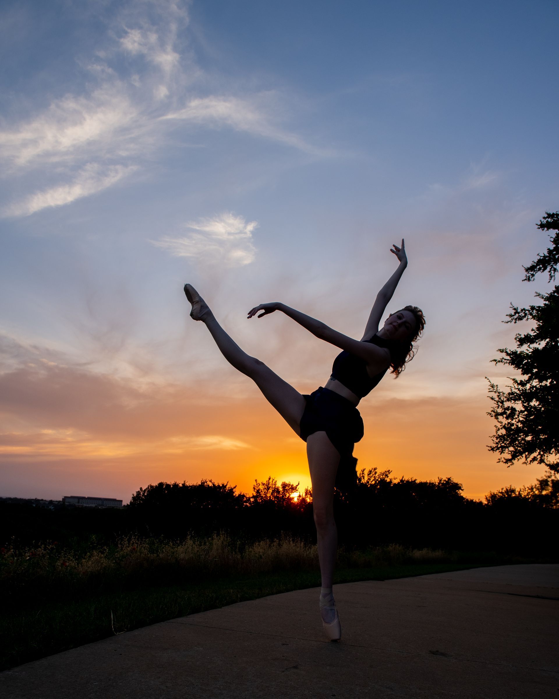 A person with long hair smiles while posing in the cockpit of a bright red vintage airplane outdoors.