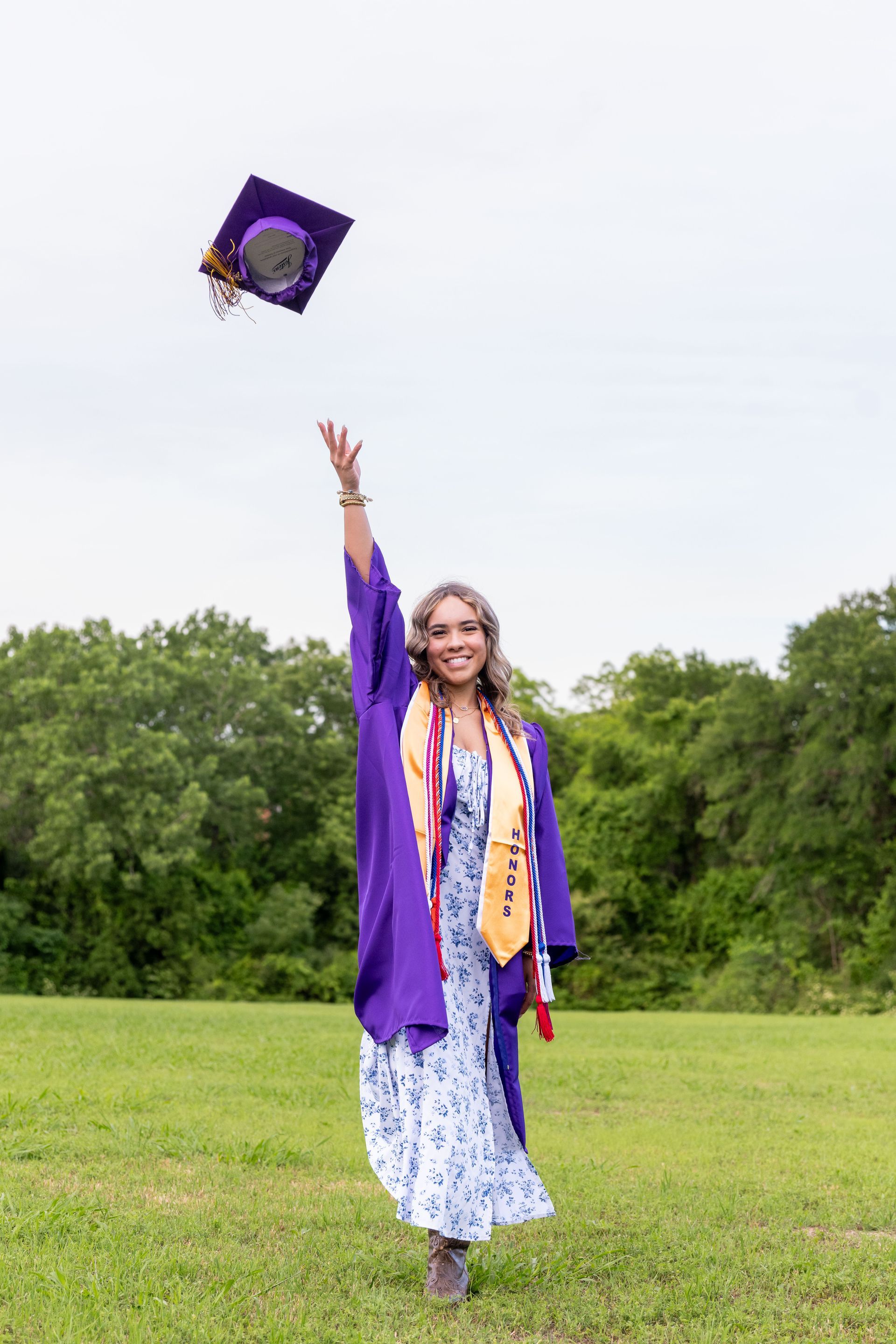 A person with long hair smiles while posing in the cockpit of a bright red vintage airplane outdoors.