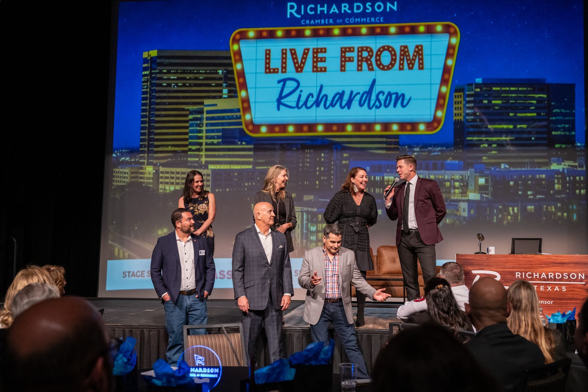 A group of people standing on a stage in front of a screen displaying 