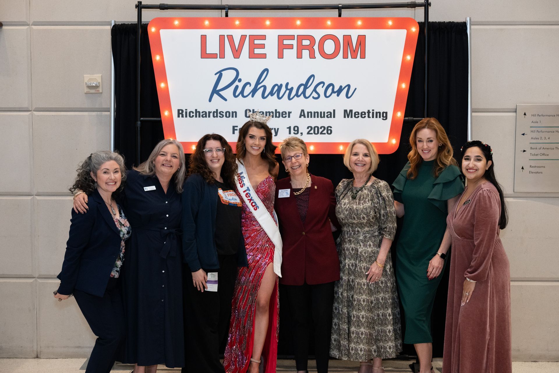 Eight people stand in front of a red-lit 
