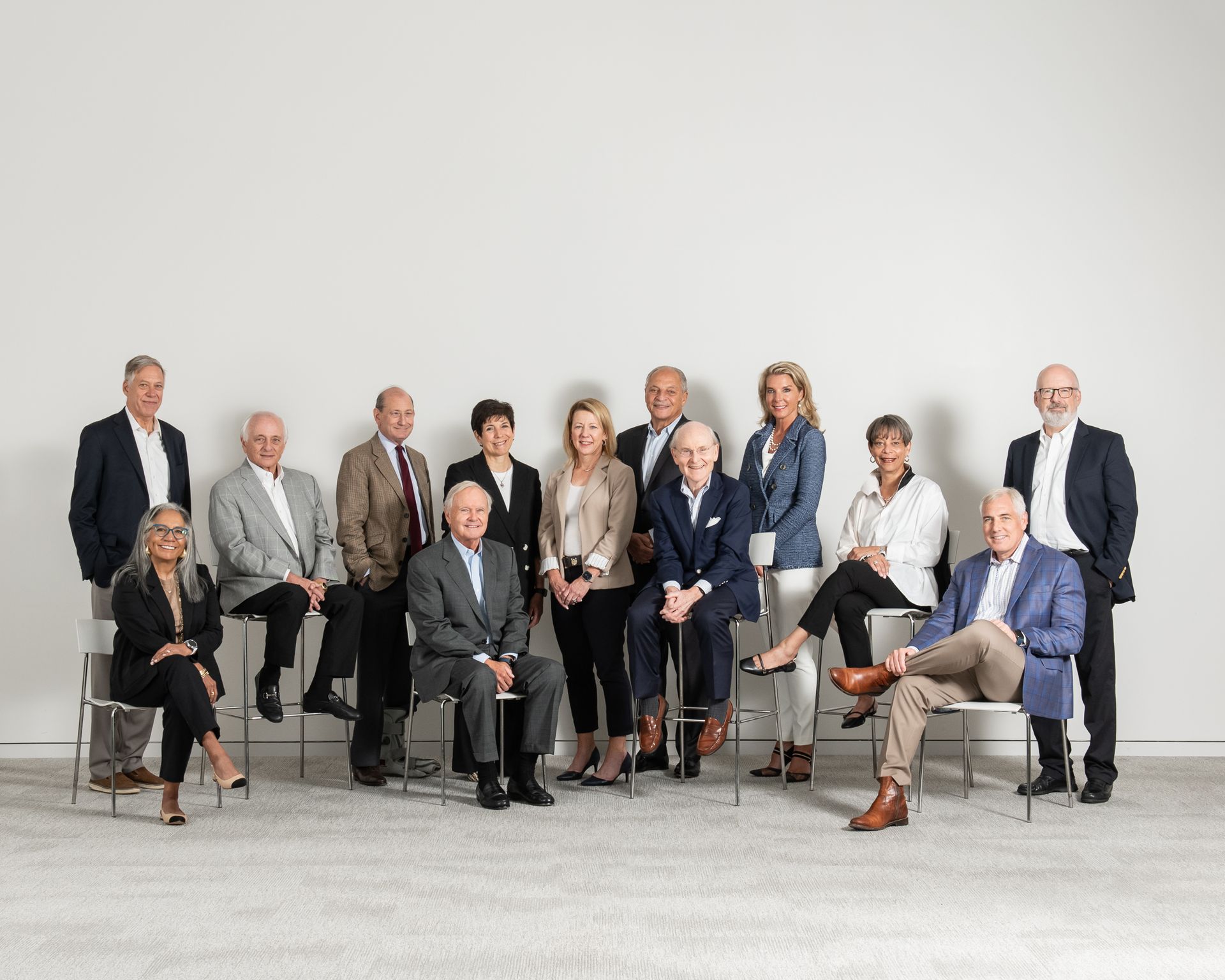 A group of twelve professional adults posed in a studio setting against a plain white background.