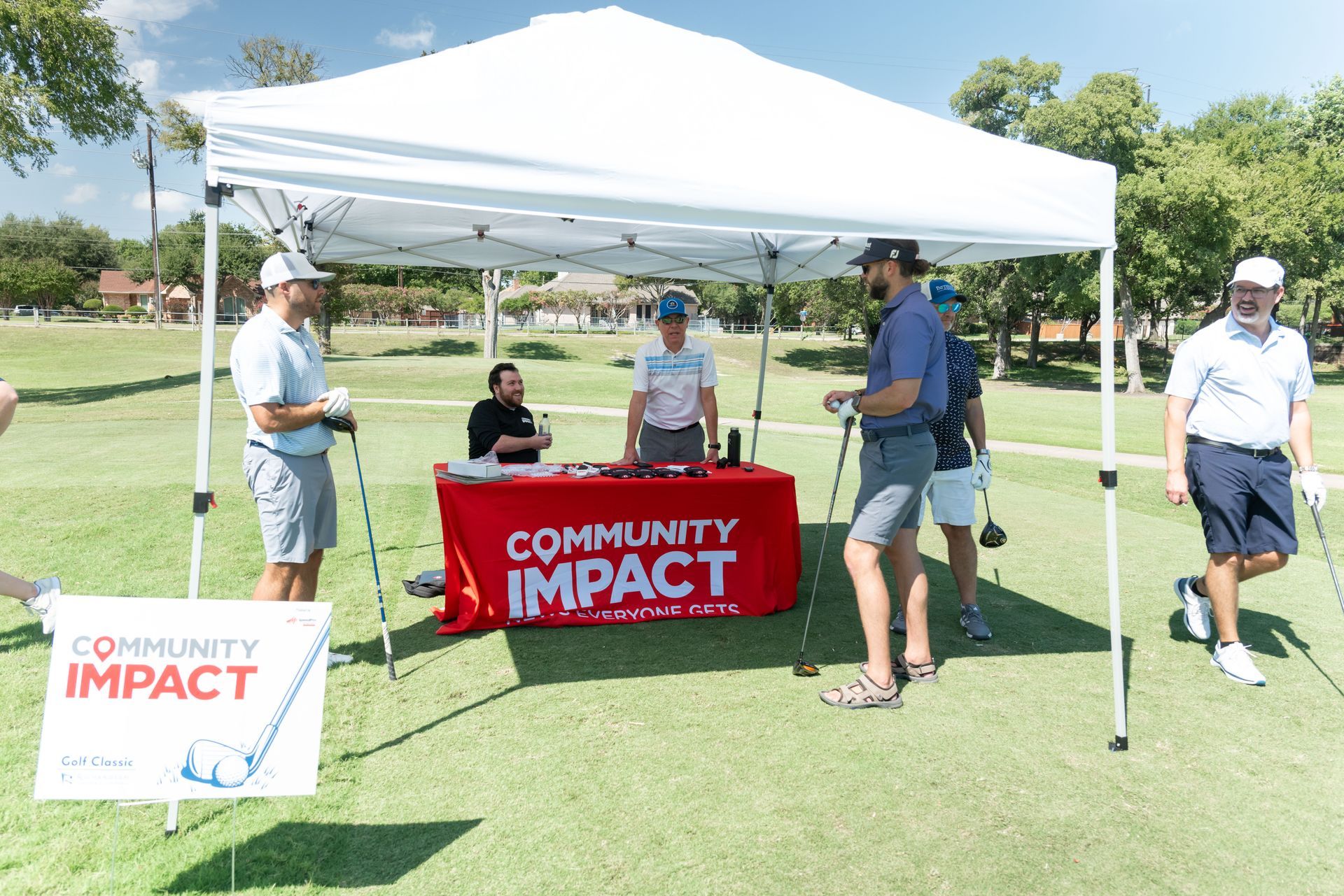 A white pop-up tent on a golf course with a red 