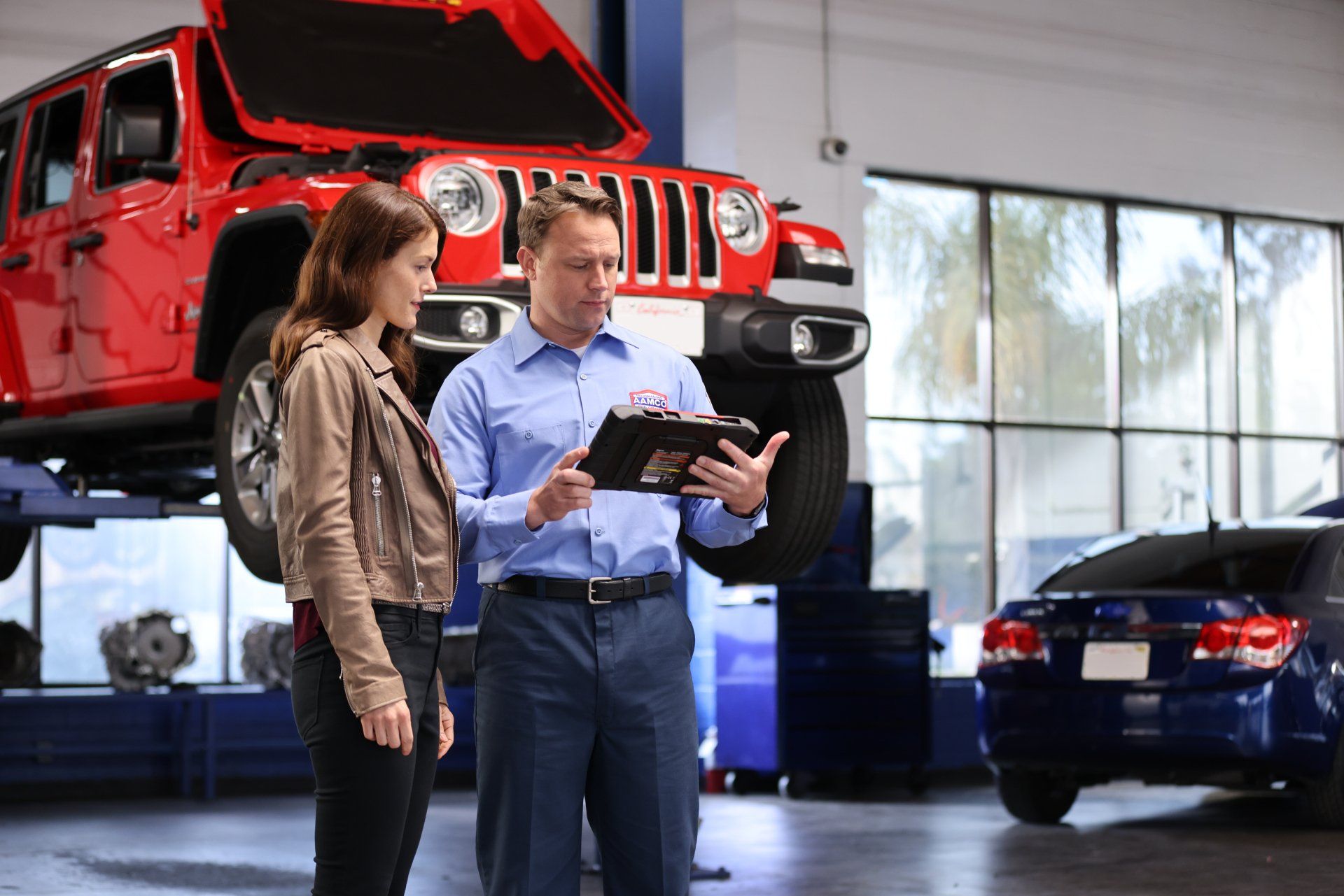 A man and a woman are looking at a clipboard in a garage.