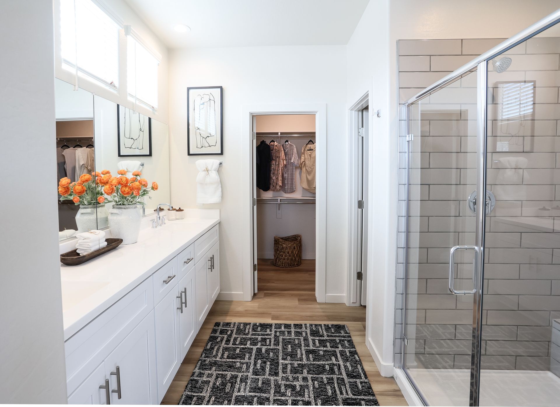 Bathroom with white cabinets, long countertop, shower, and walk-in closet.