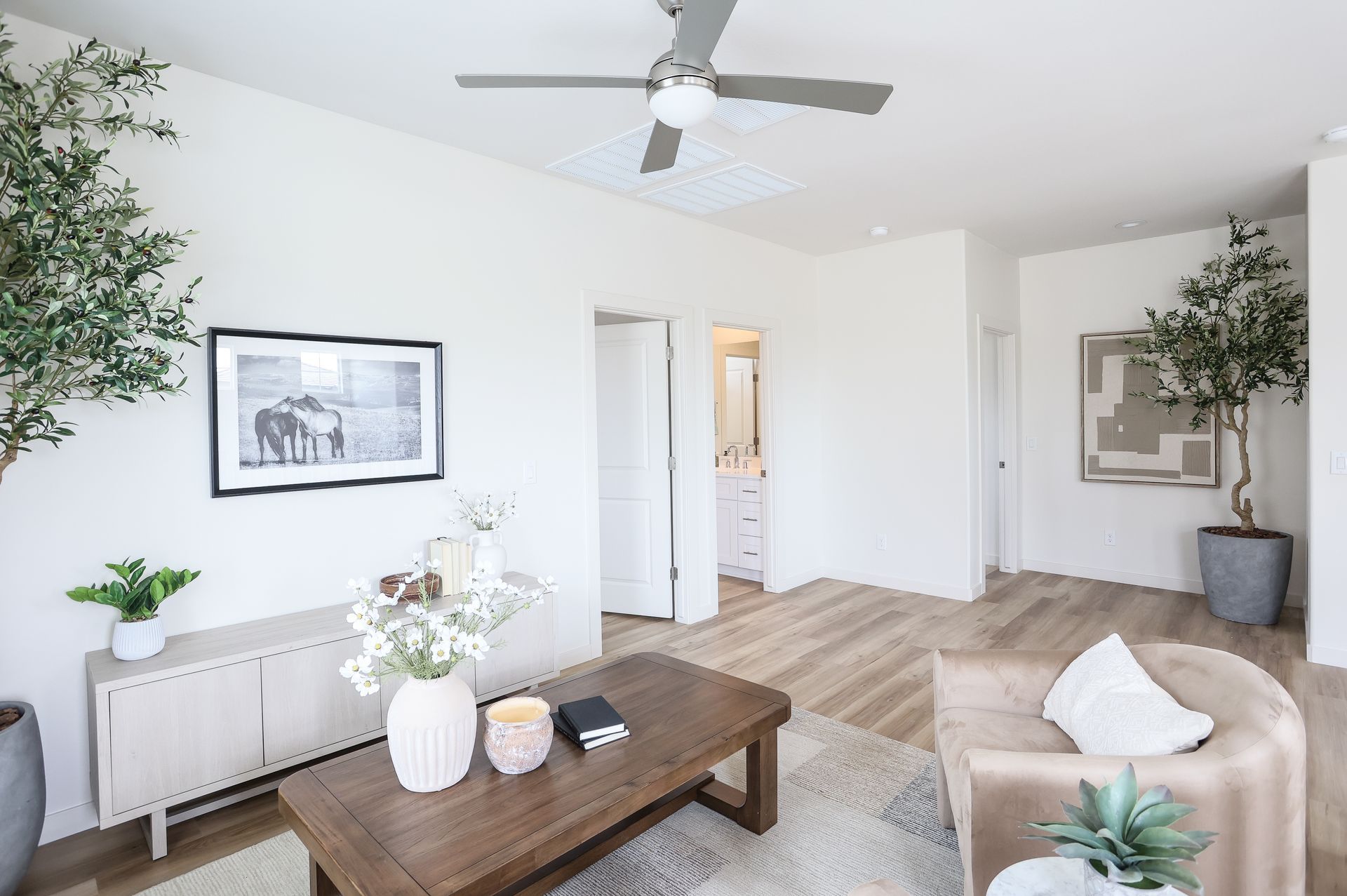Living room with light wood floors, white walls, and neutral furniture.