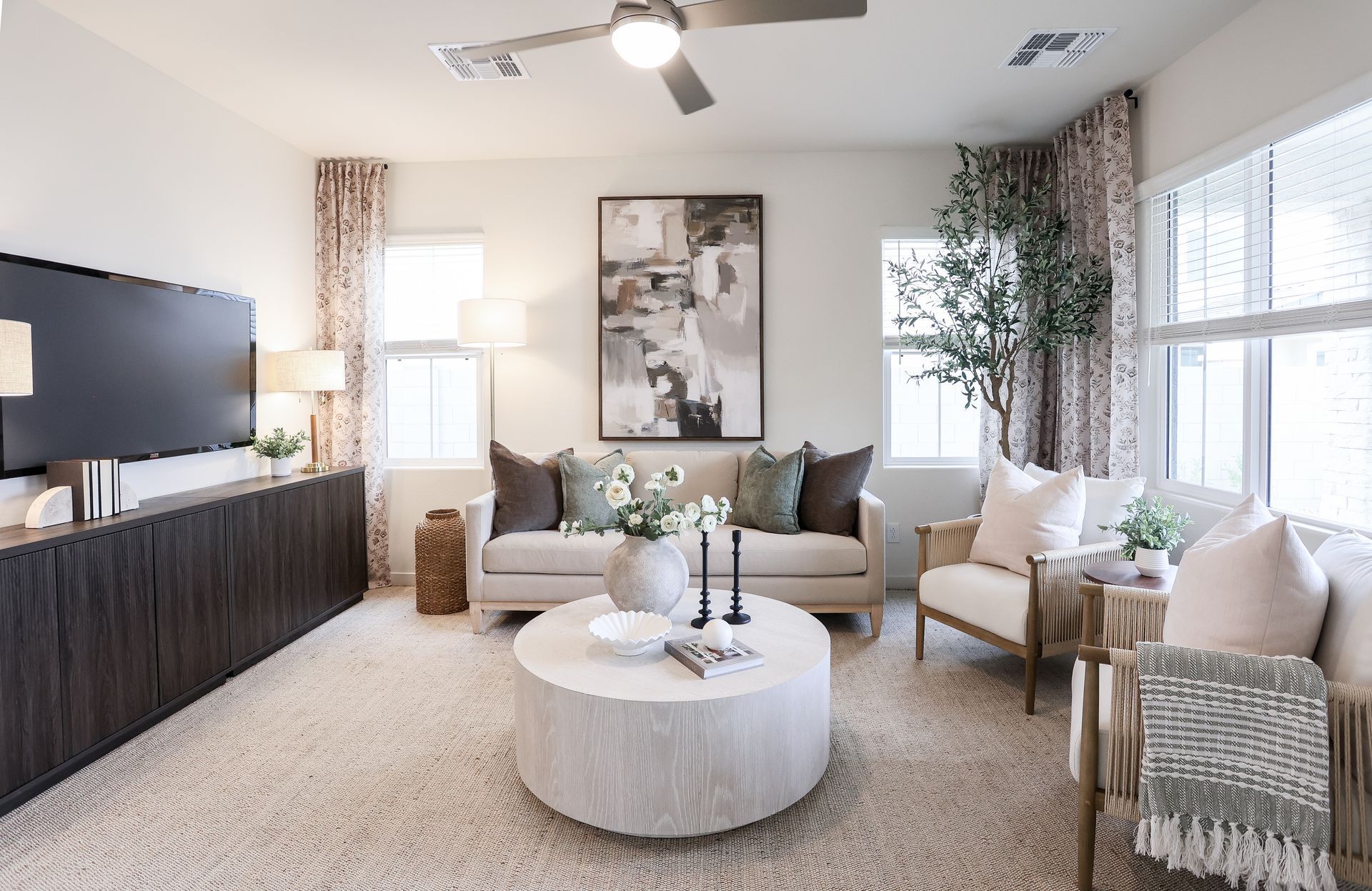 Living room with neutral tones, large TV, cream sofa, and round coffee table.