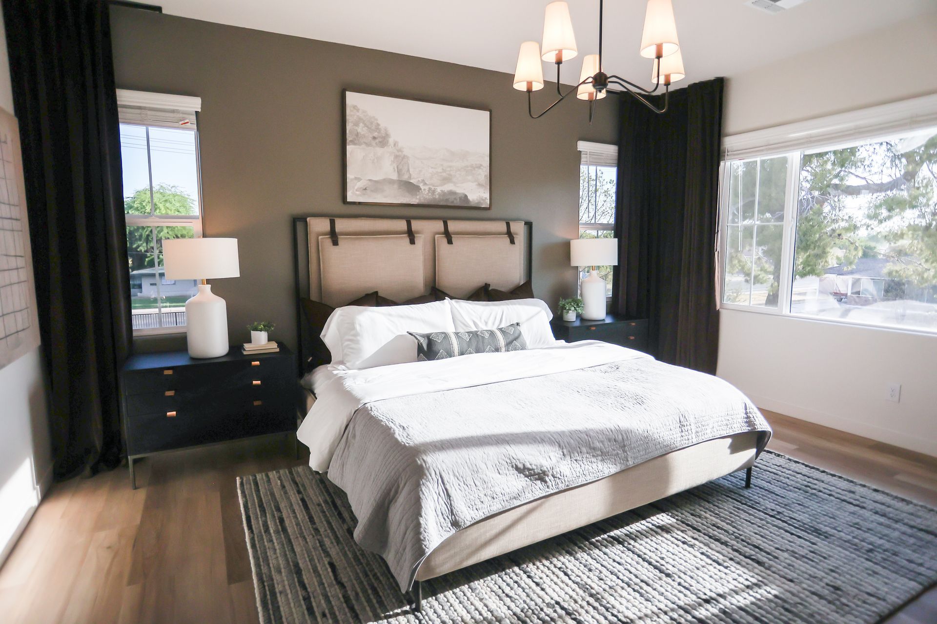 Bedroom with a bed, nightstands, windows, rug, and dark gray wall.