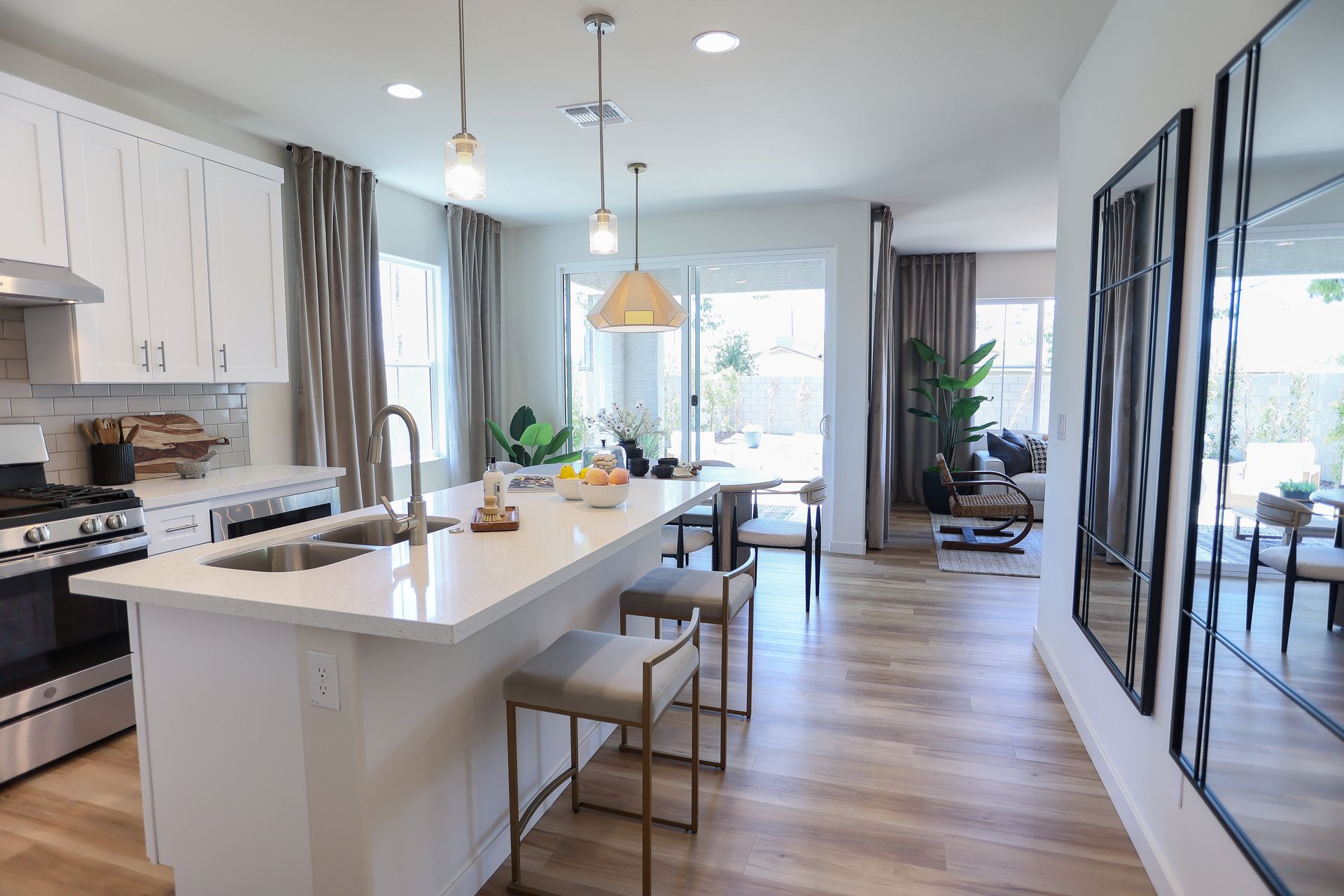 Modern kitchen with white cabinets, island with stools, and open plan to living area.