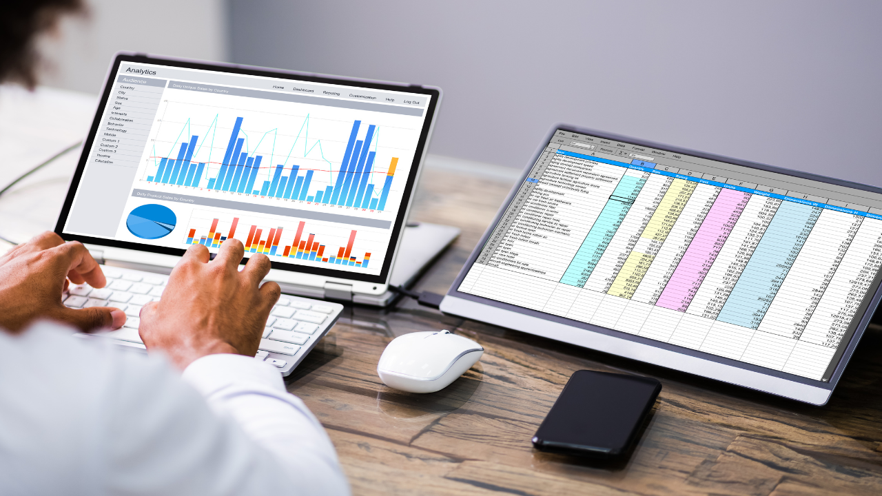 A man is using a laptop and a tablet with graphs on them