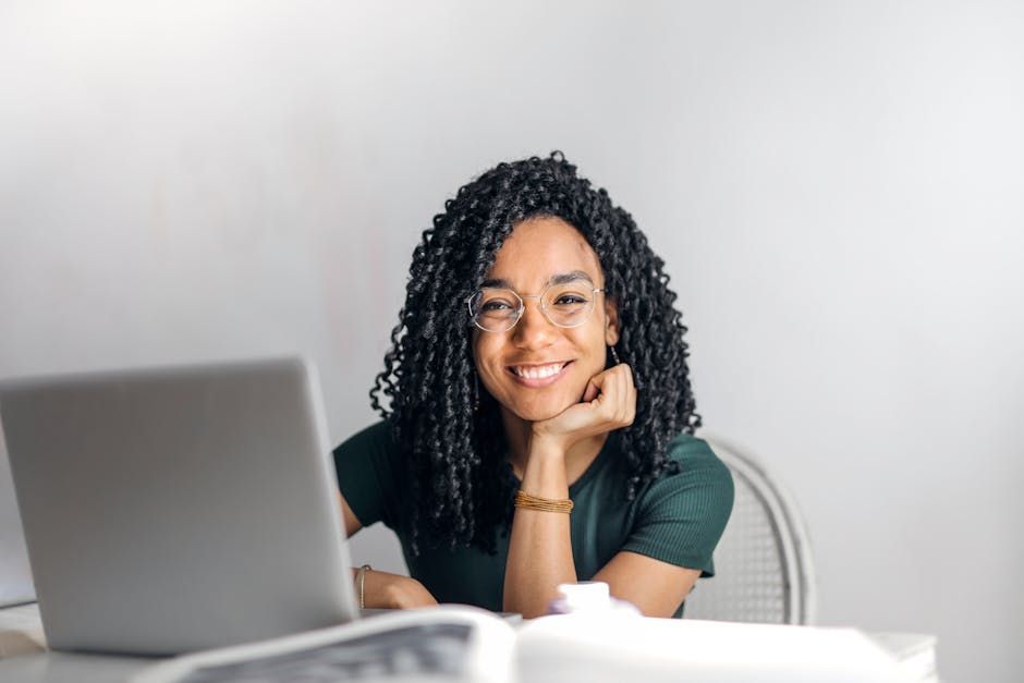 A woman is sitting at a desk in front of a laptop computer.