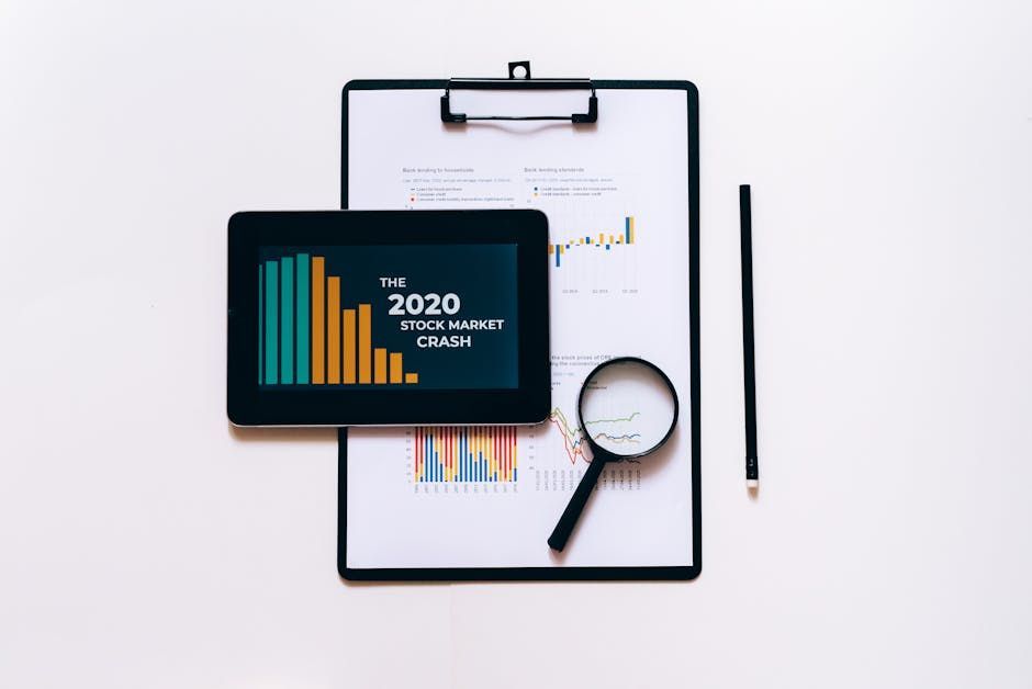 A tablet is sitting on top of a clipboard next to a magnifying glass and a pencil.