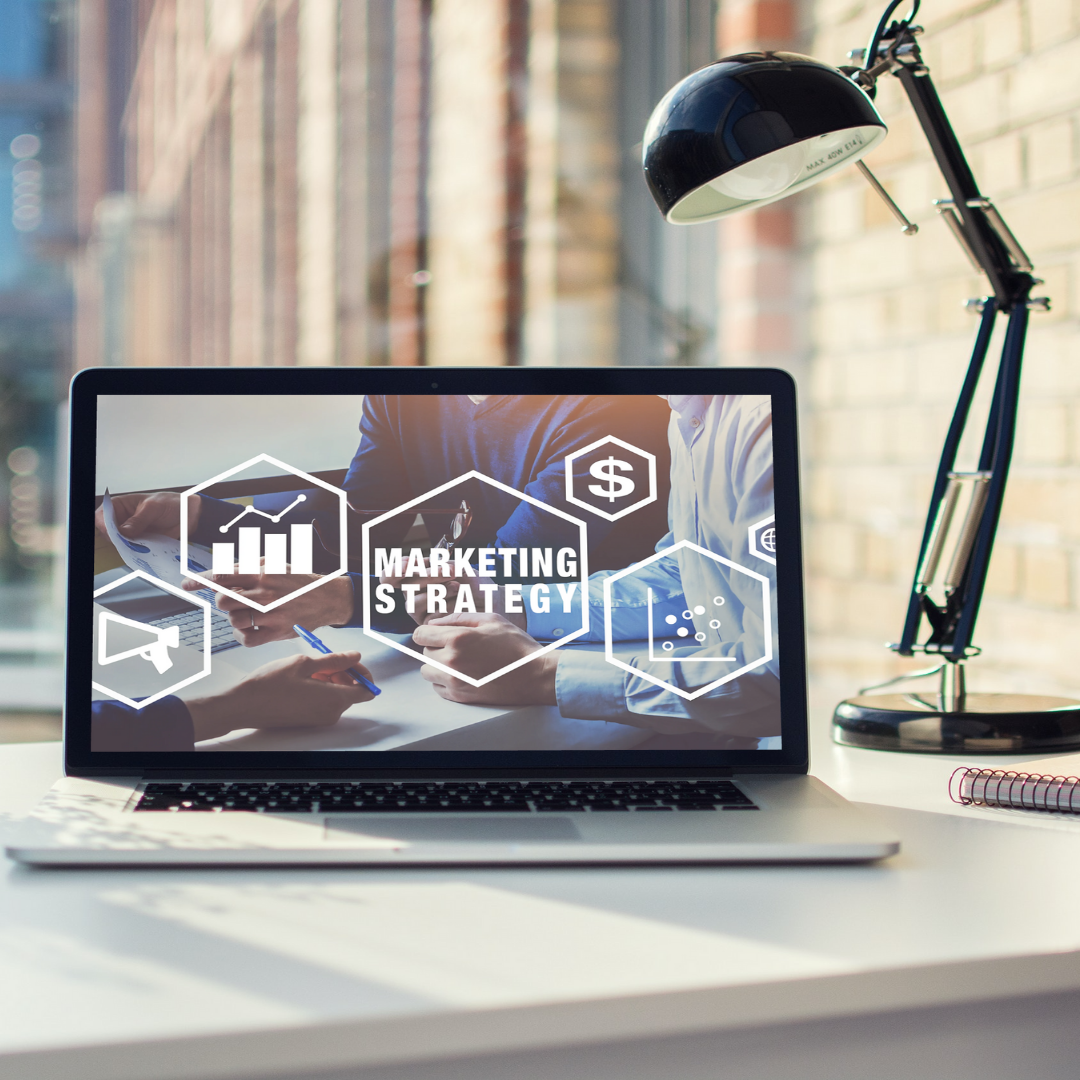 A laptop computer is open to a screen that says marketing strategy