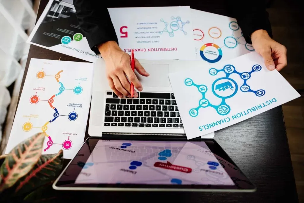 A person is sitting at a table with a laptop and papers on it.