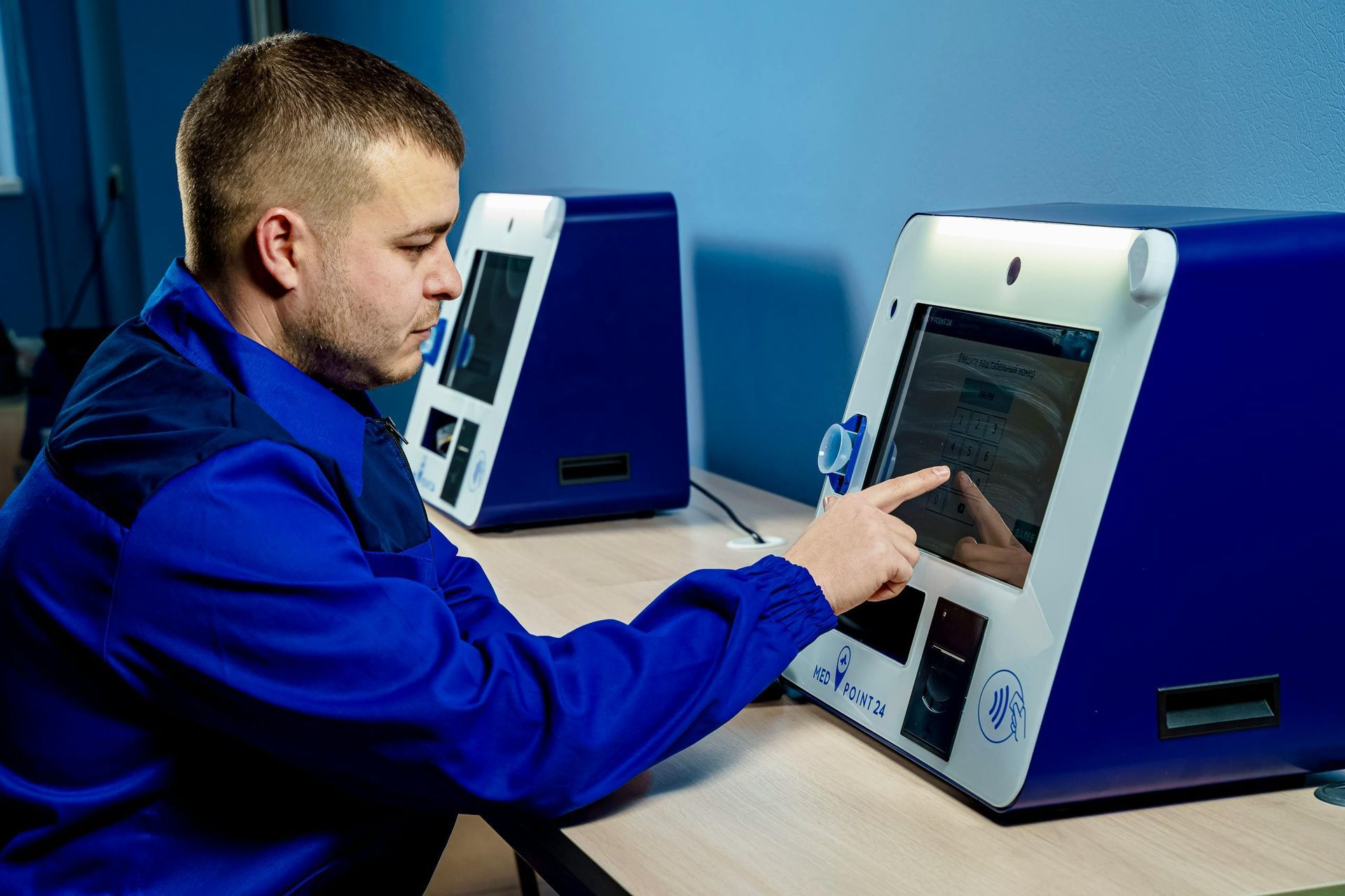 A man in a blue uniform is pointing at a machine