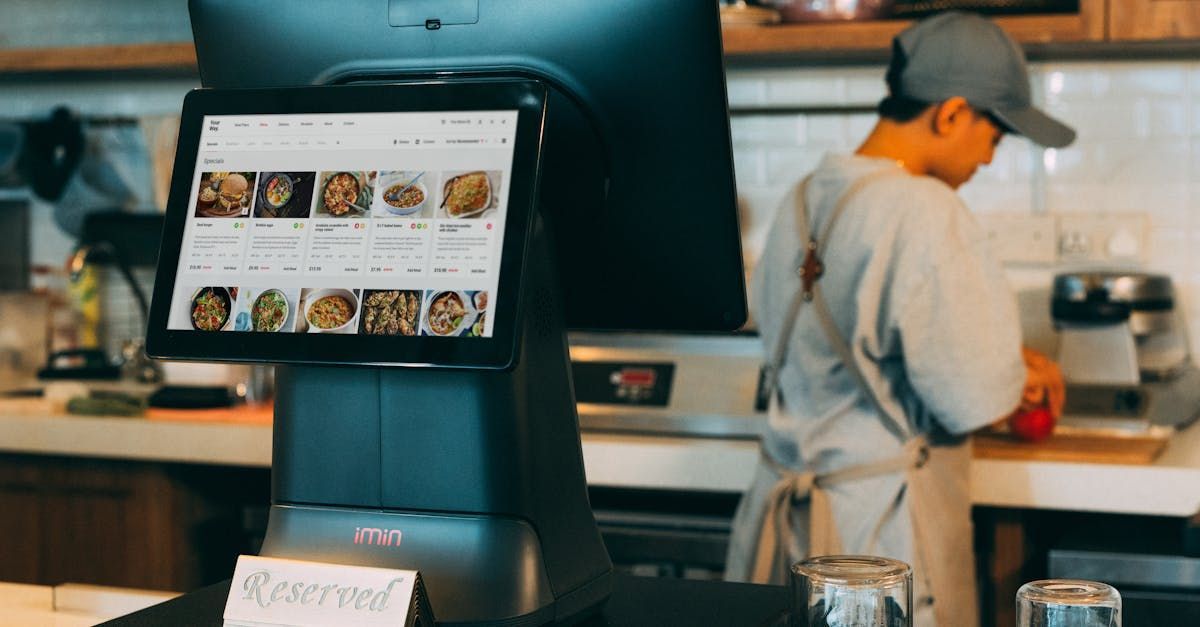 A man is standing in front of a computer in a restaurant.