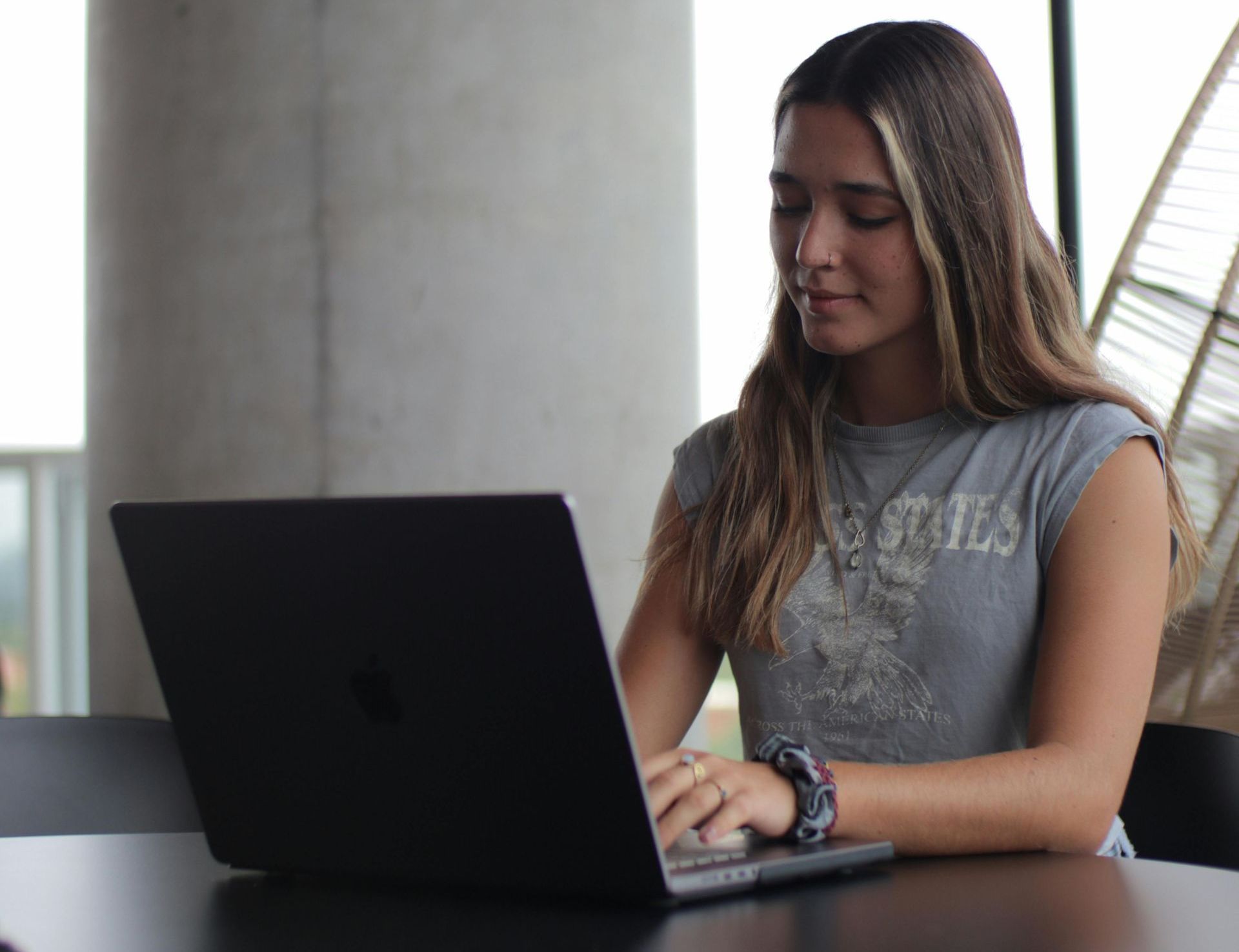 A woman is sitting at a table using a laptop computer.