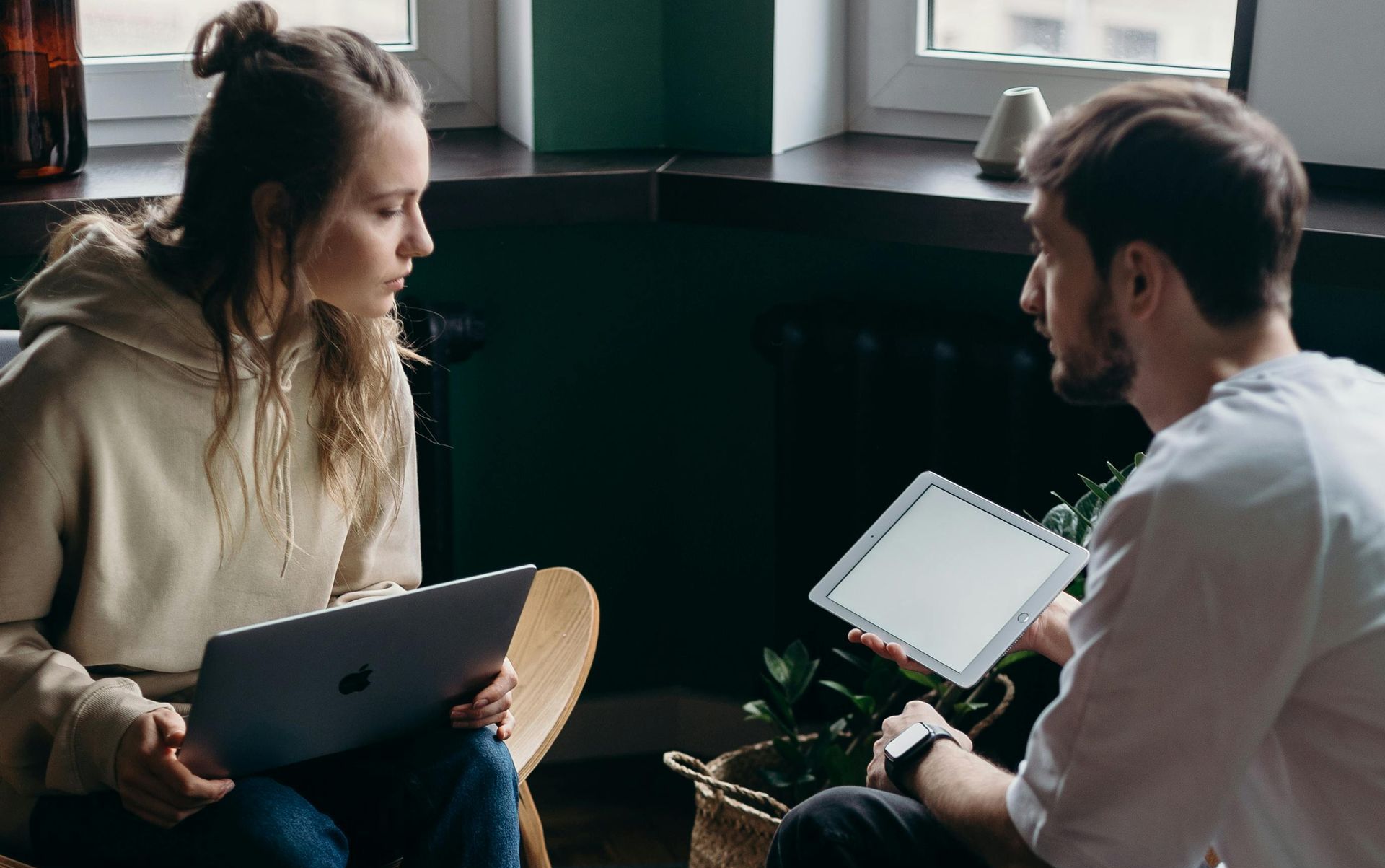 A man and a woman are sitting on the floor looking at a tablet.