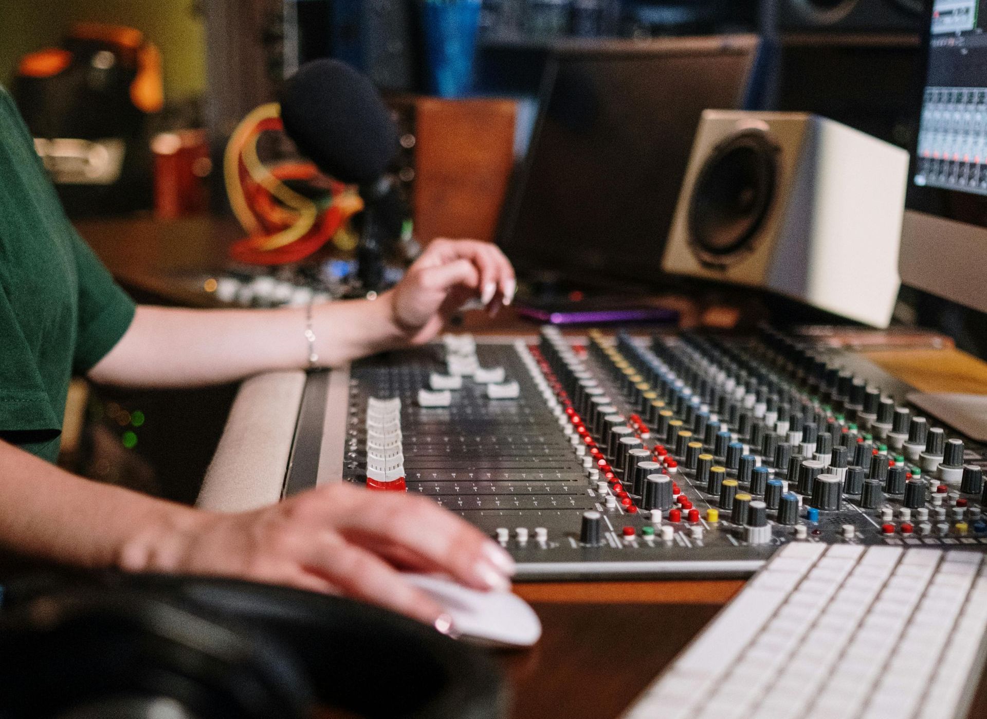 A woman is using a computer mouse and keyboard in a recording studio.