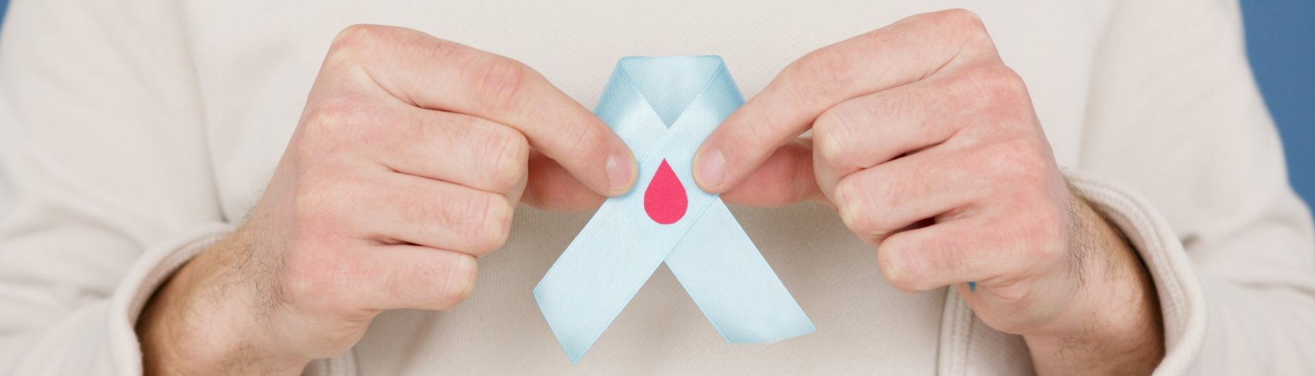 A person is holding a blue ribbon with a red cross on it.