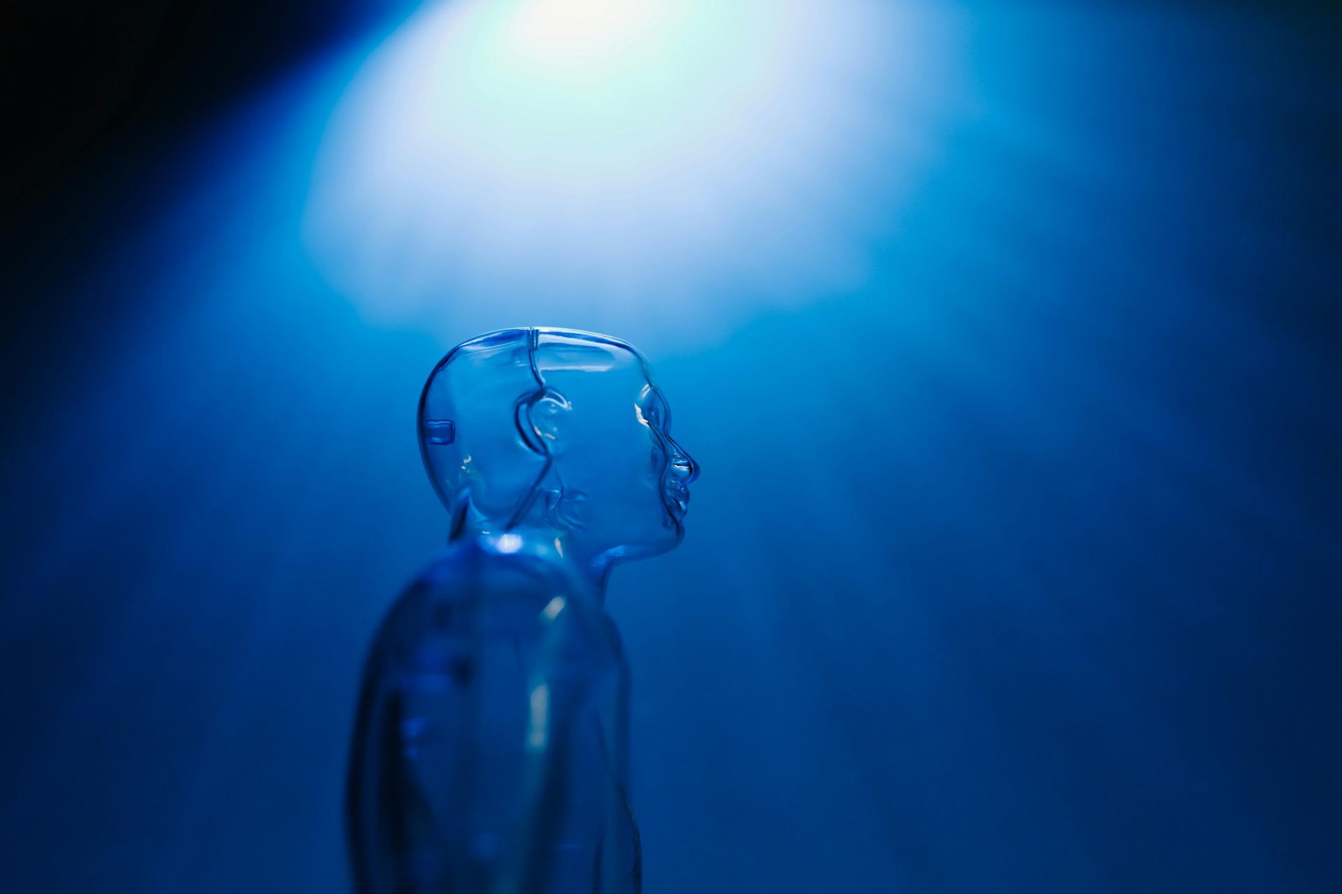 A broken glass head is standing in front of a blue light.