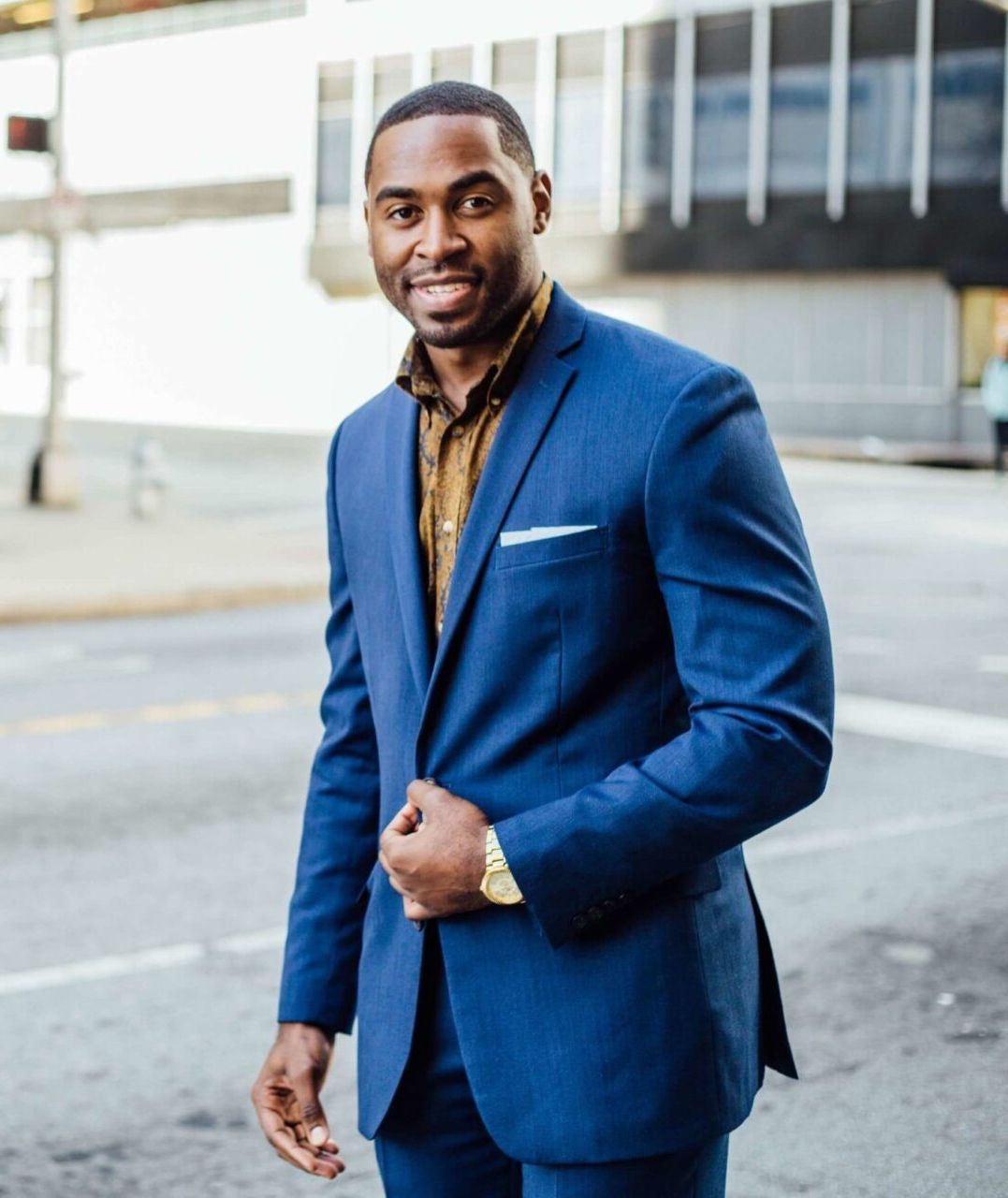 A man in a blue suit is standing on a city street