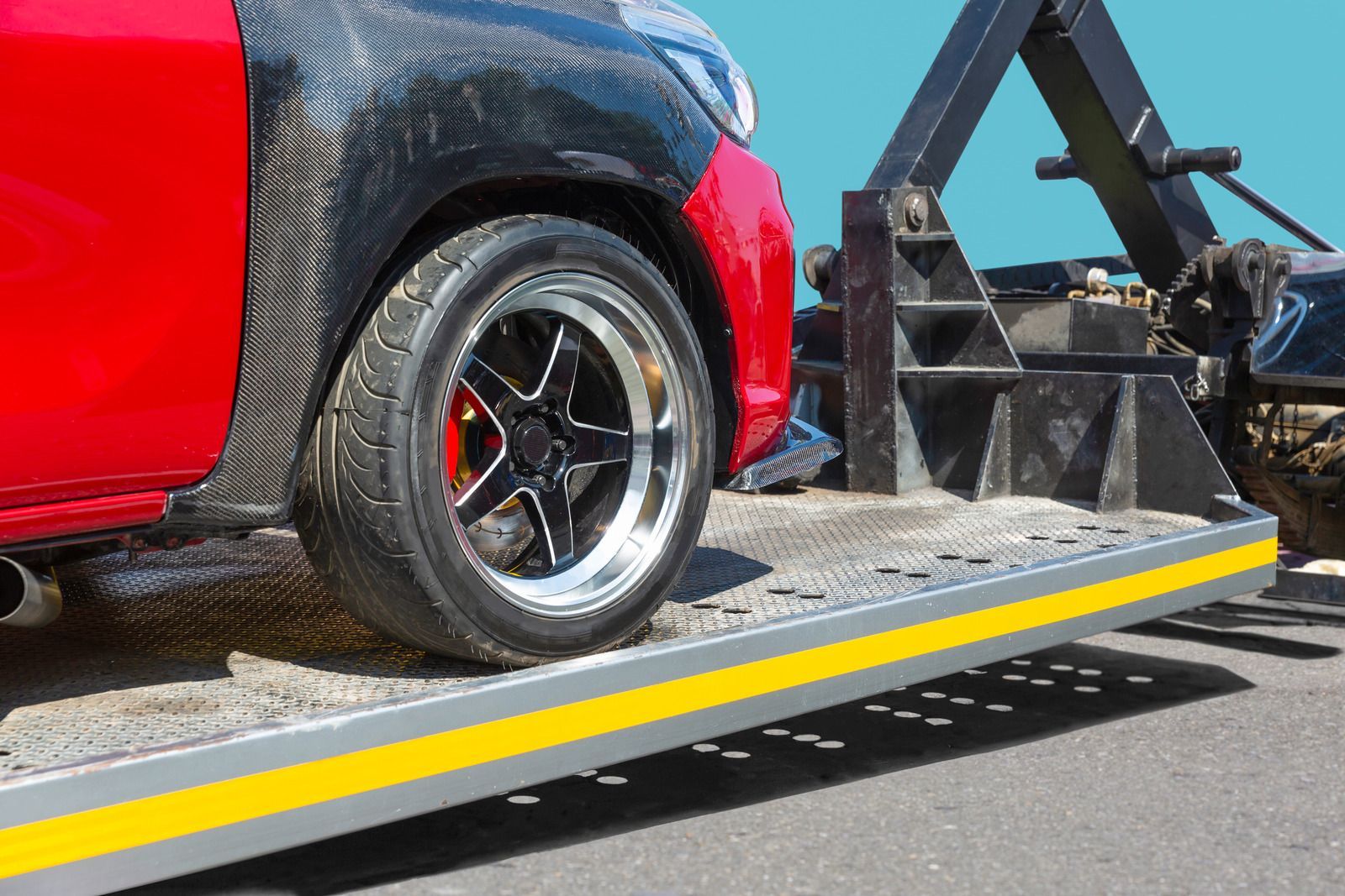 A red car is being towed by a tow truck.