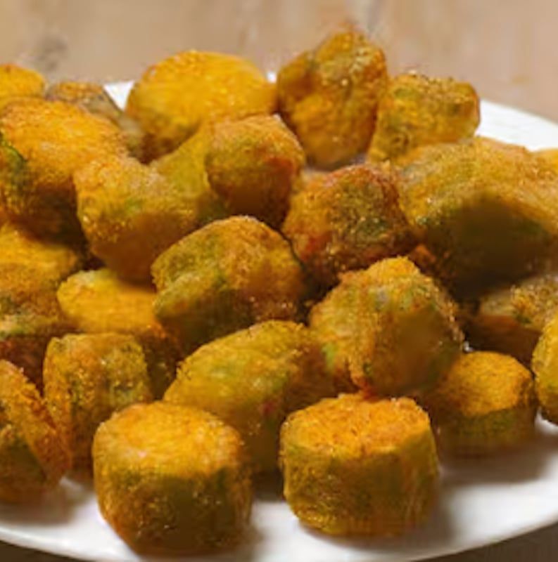 A white plate topped with fried green beans on a table.