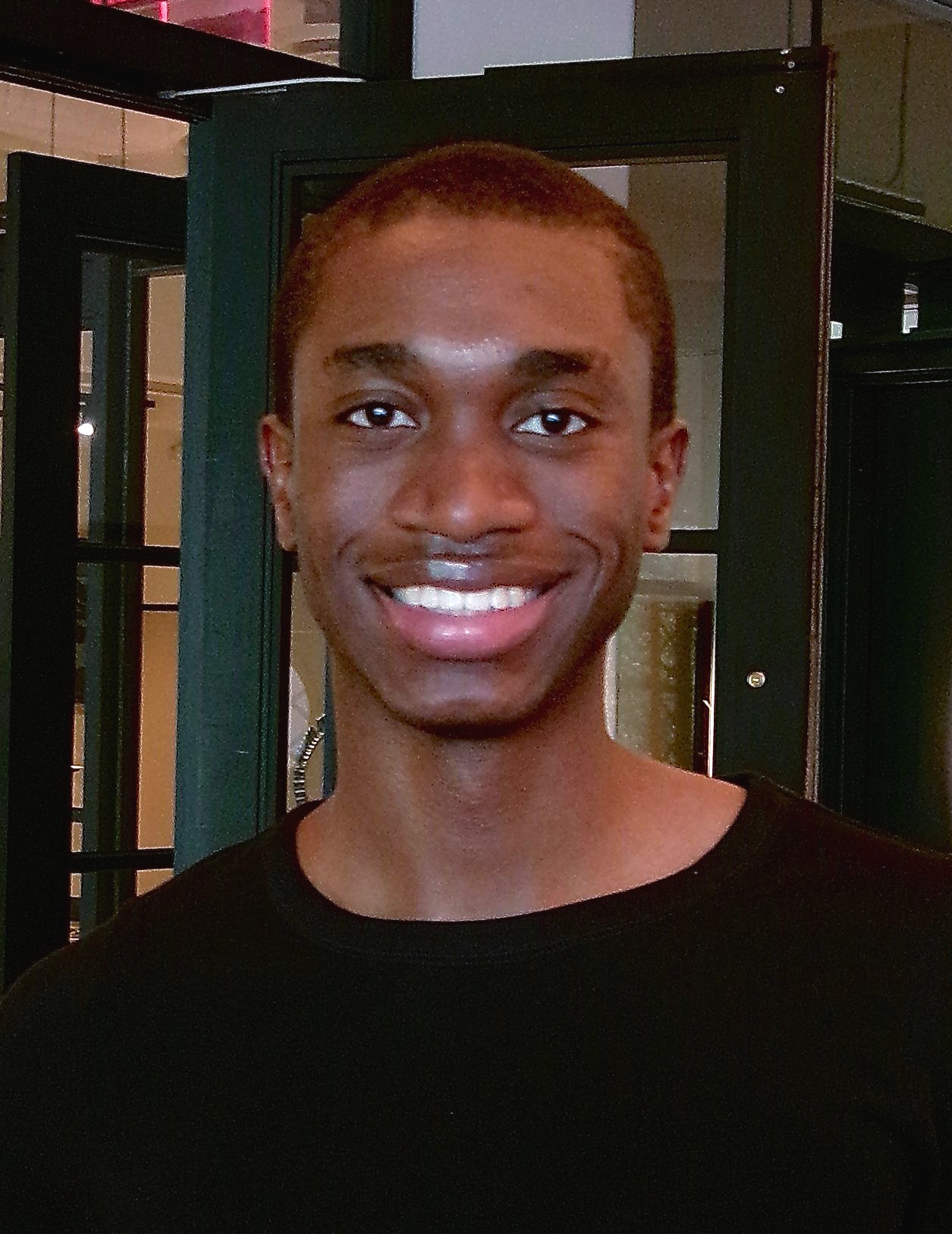 Dark haired man in black long sleeved shirt smiles for camera.