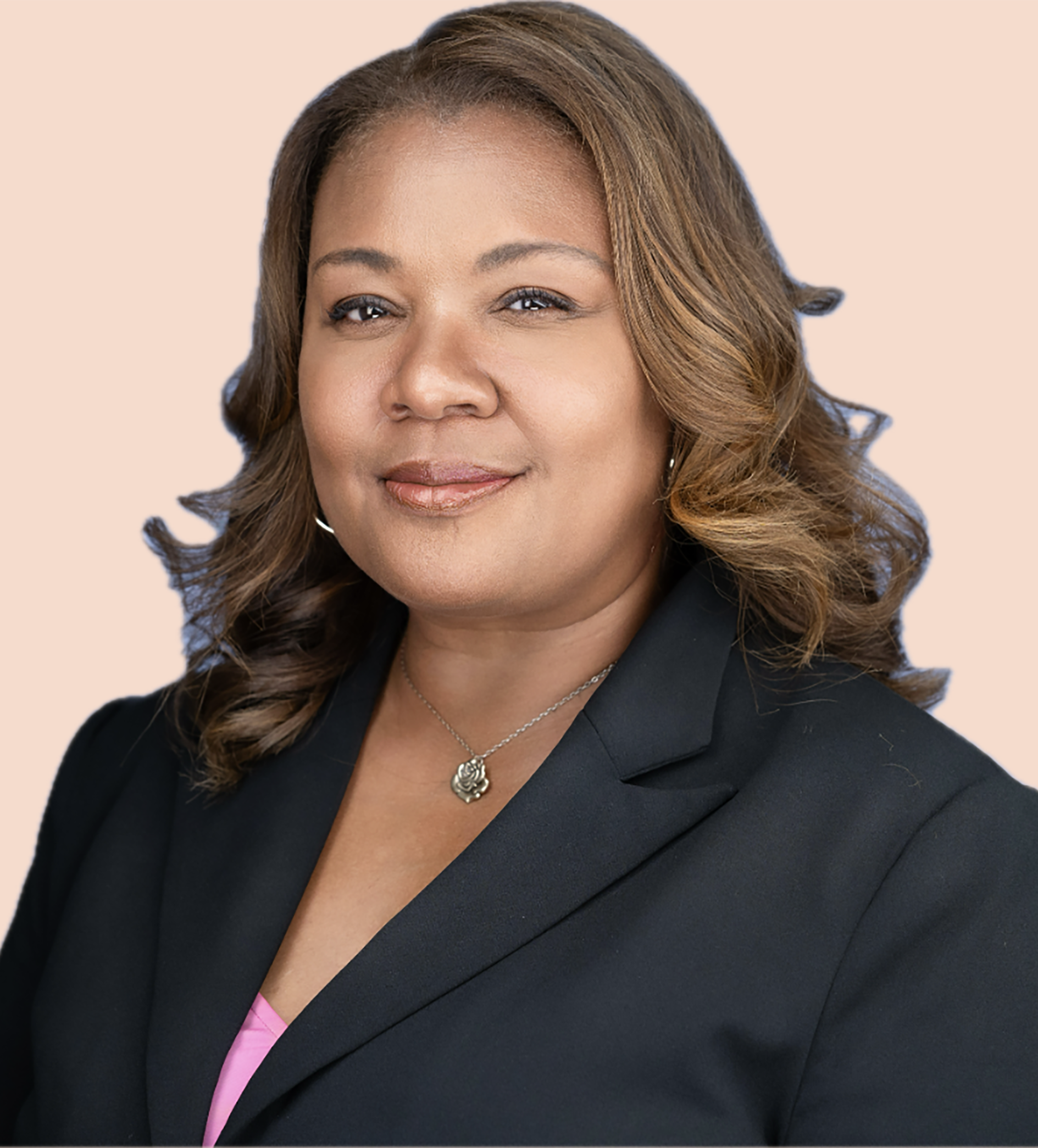 Woman in black blazer smiles, wearing a necklace.