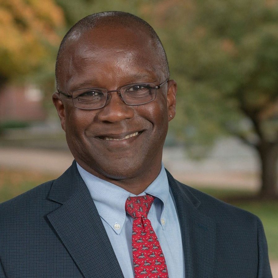 A man in a suit and tie is smiling for the camera.