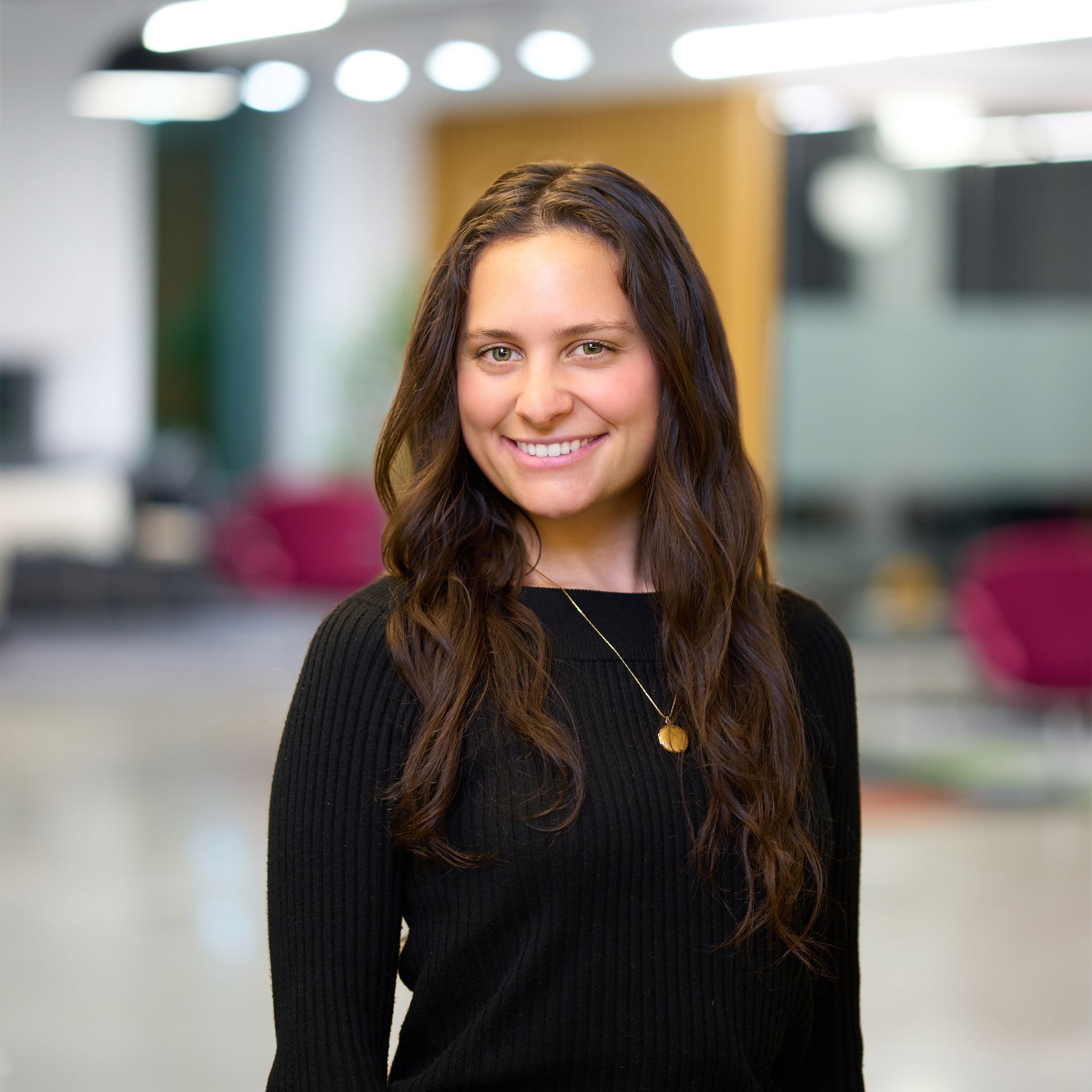 Woman with long dark hair smiles, wearing a white button-down shirt.