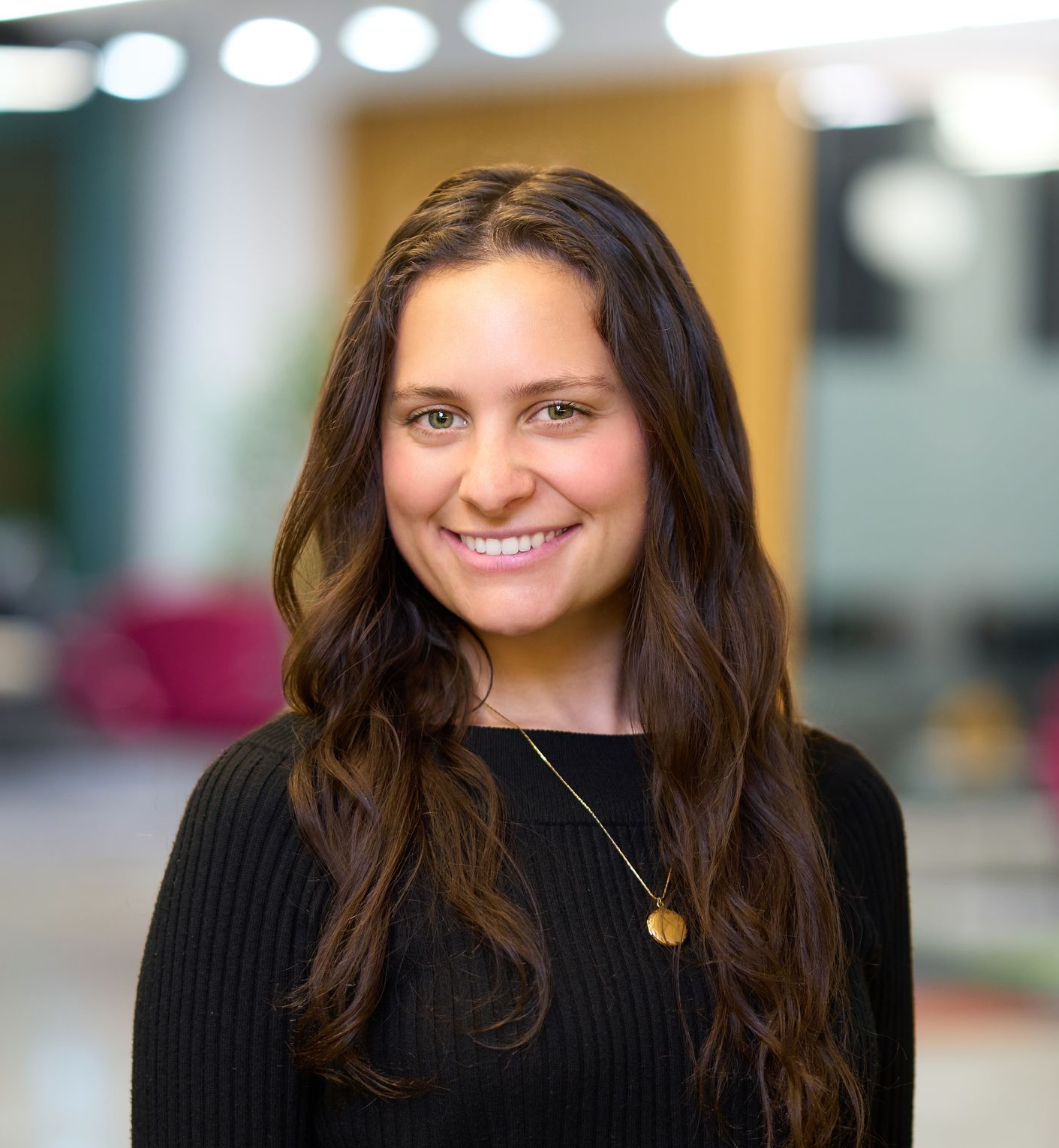 Woman smiling, wearing a black shirt, with long brown hair.