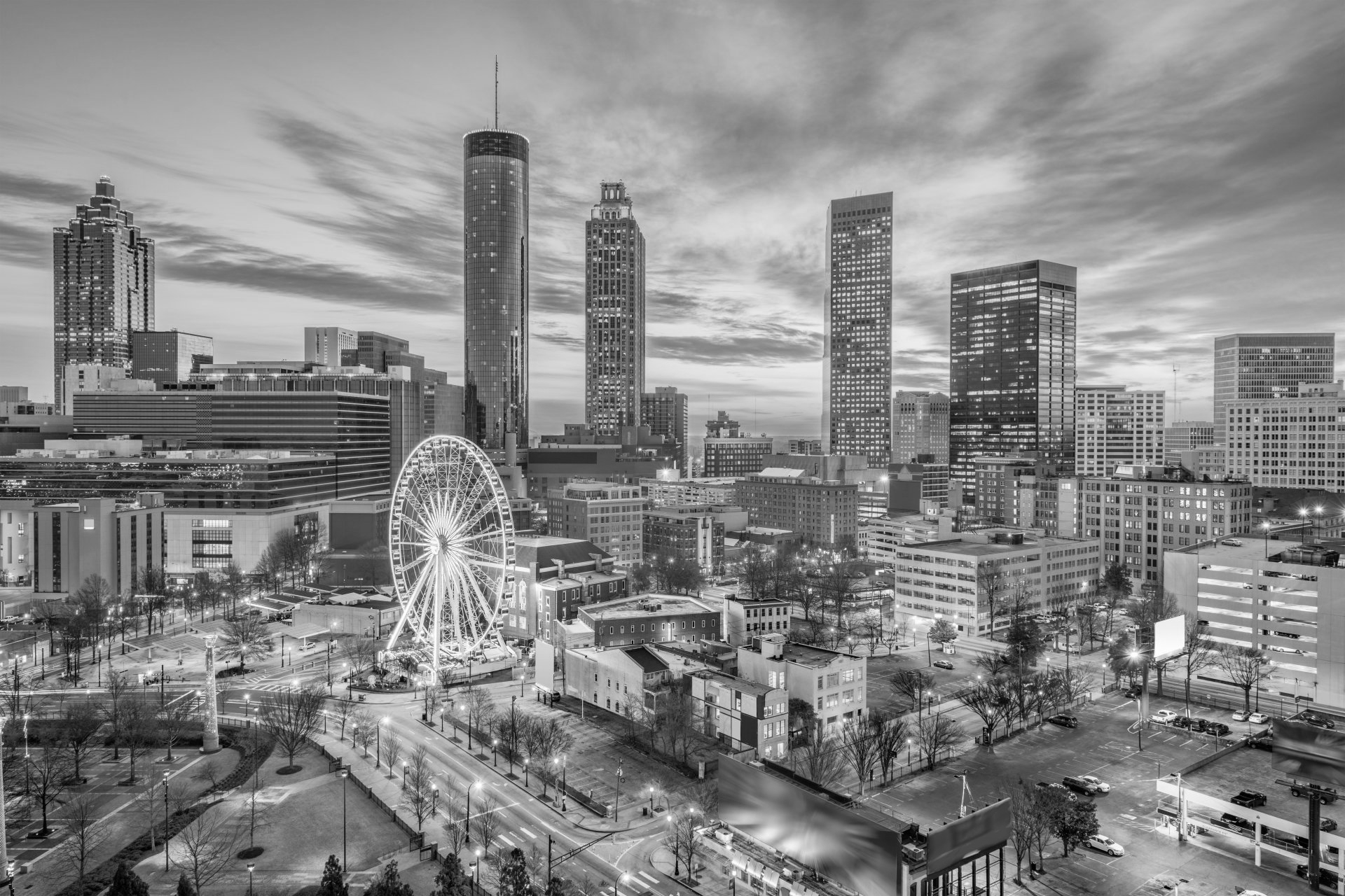 A black and white photo of a city skyline with a ferris wheel in the foreground.