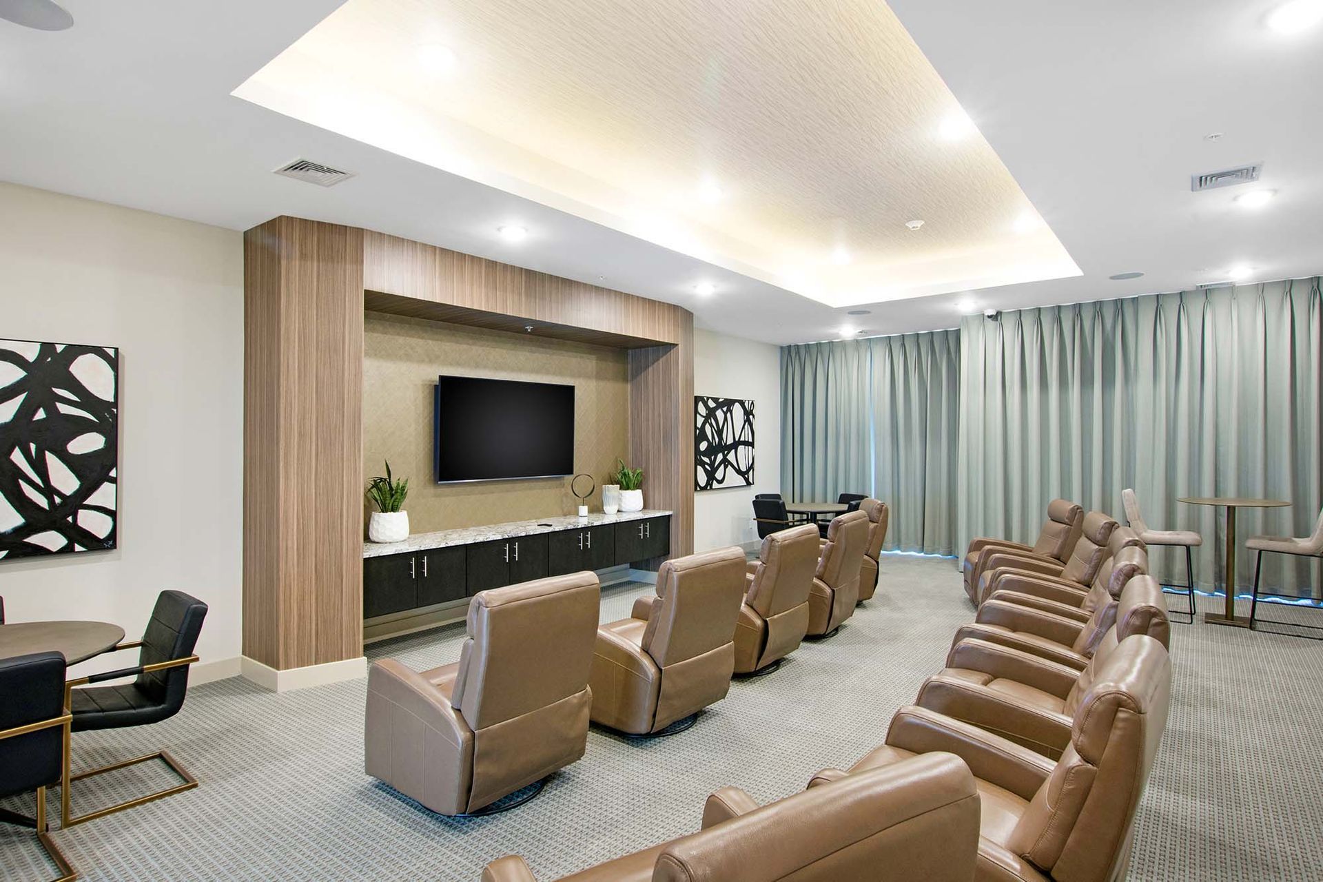 Common area lounge with rows of tan leather recliners facing a wall-mounted TV at The Parc at Roxbury in  Roxbury, NJ.