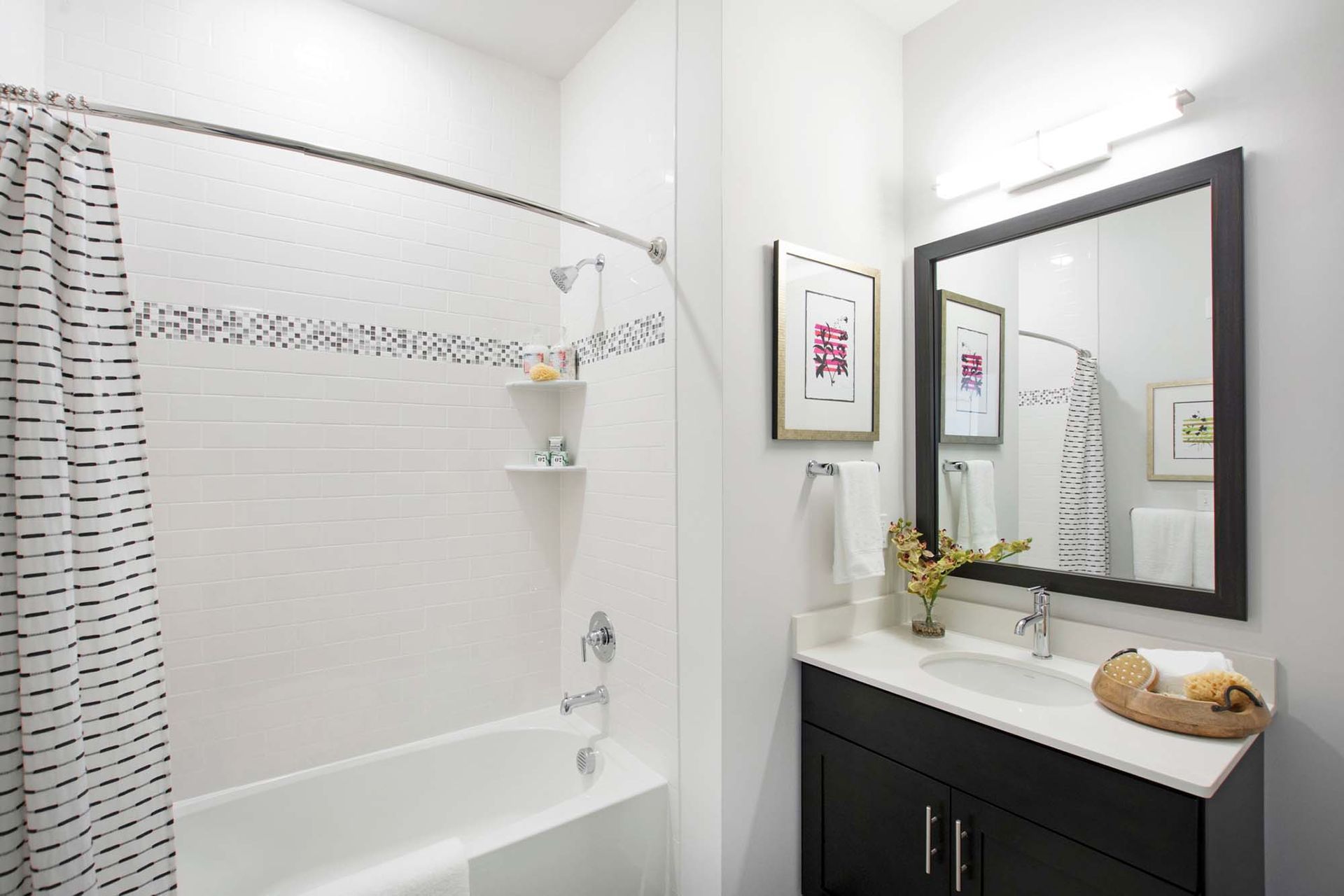 Bathroom in apartment: white tiled shower, striped curtain, dark vanity with mirror at The Parc at Roxbury in  Roxbury, NJ.