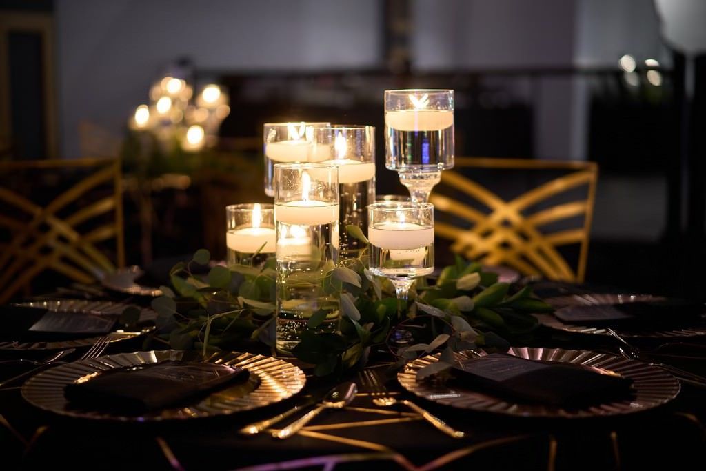 A table set for a wedding reception with plates and candles on it.