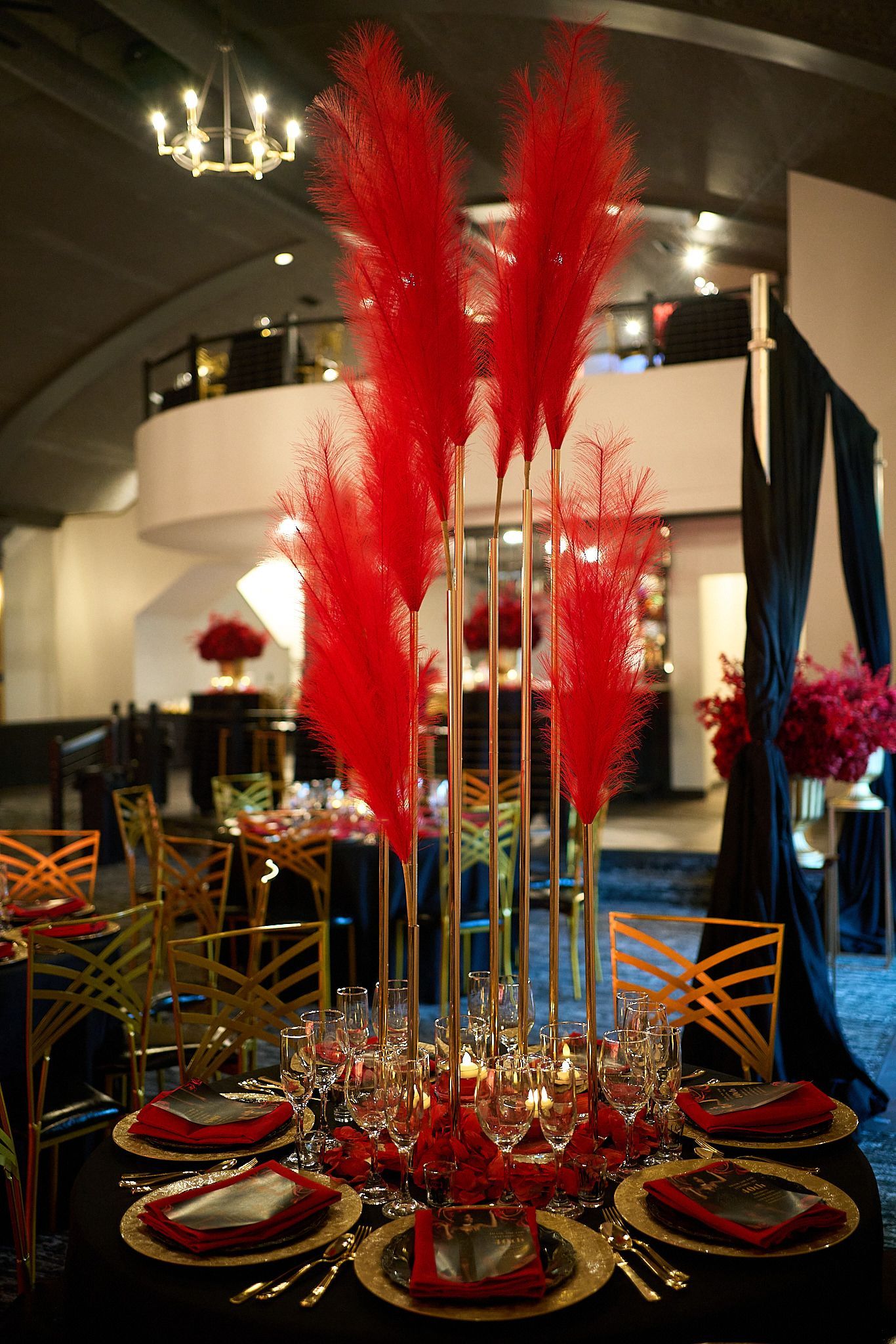 A table with plates , candles , and red flowers on it.