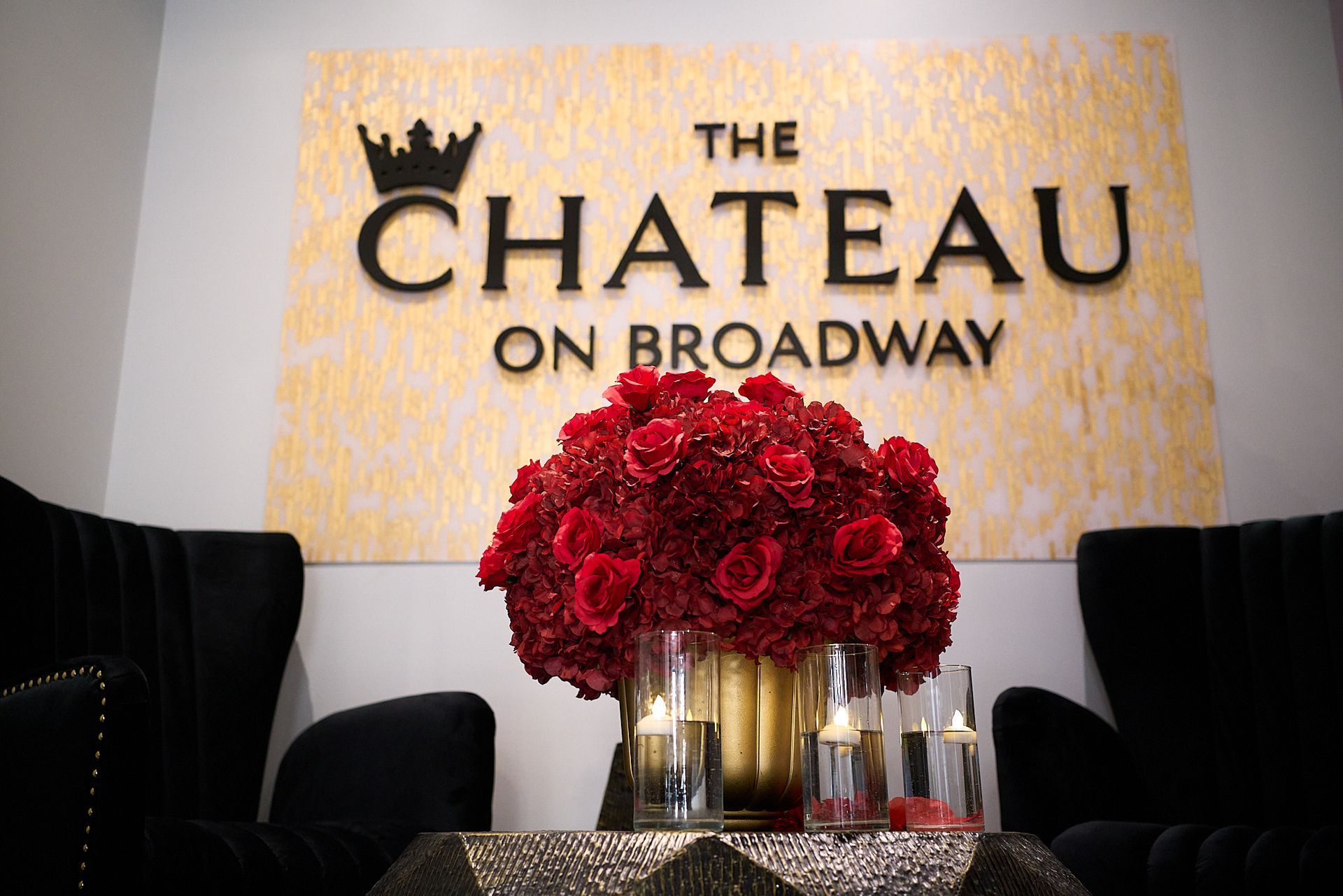A table with flowers and candles in front of a sign that says the chateau on broadway