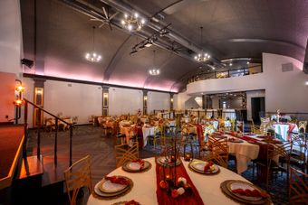 A large room with tables and chairs set up for a wedding reception