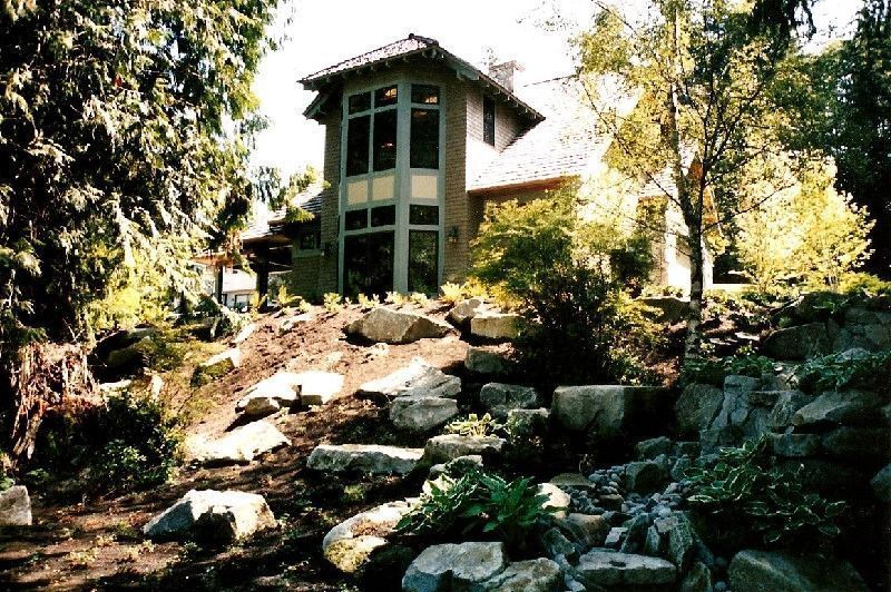 A house with a lot of windows sits on top of a rocky hill.